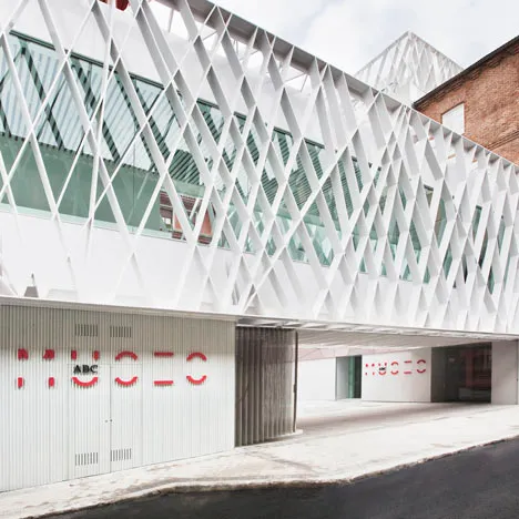 Modern building with white geometric lattice facade and red 'MUSEO' lettering on a white wall