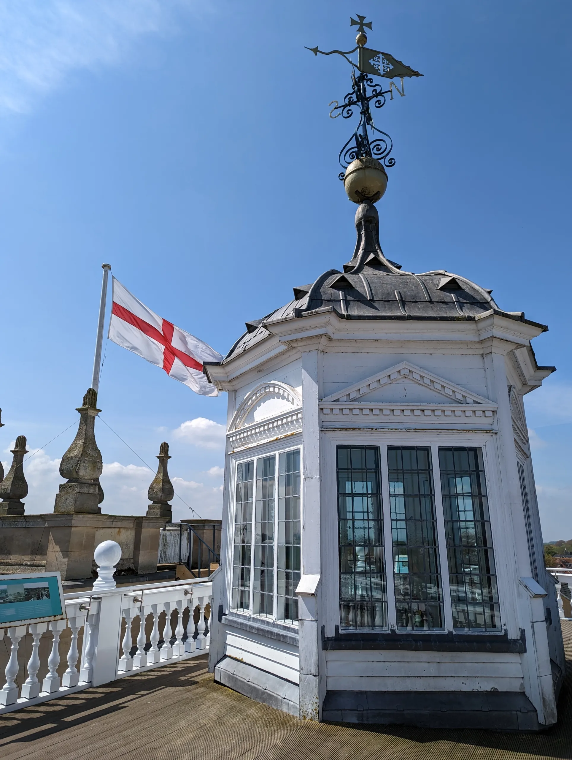 Cúpula octogonal blanca con veleta de hierro ornamentada sobre el tejado del Abingdon County Hall Museum, con la bandera de la Cruz de San Jorge ondeando contra un cielo azul