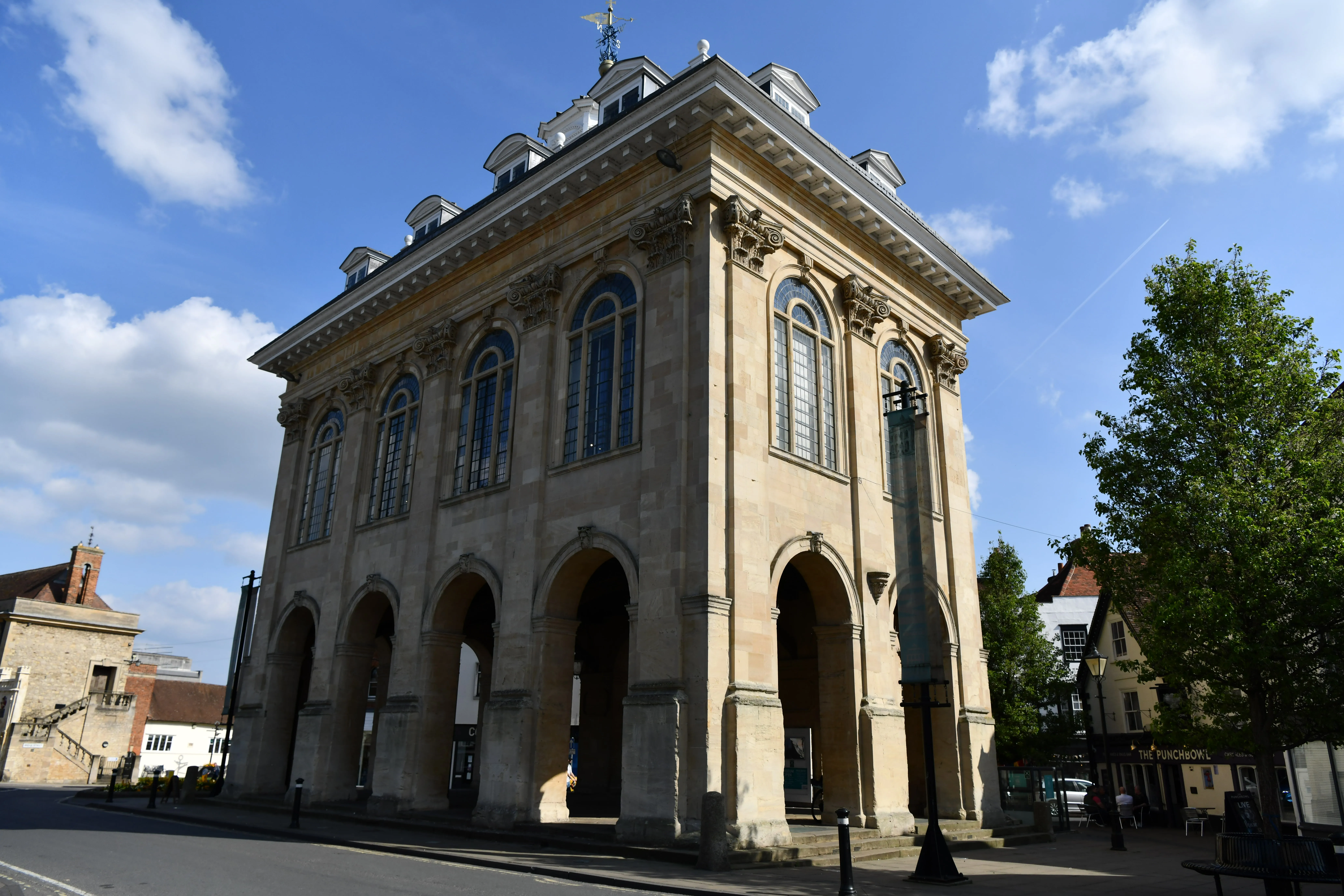 Fachada de piedra del Abingdon County Hall Museum con aberturas arqueadas en la planta baja, ventanales altos y una línea de techo con balaustrada sobre un cielo azul