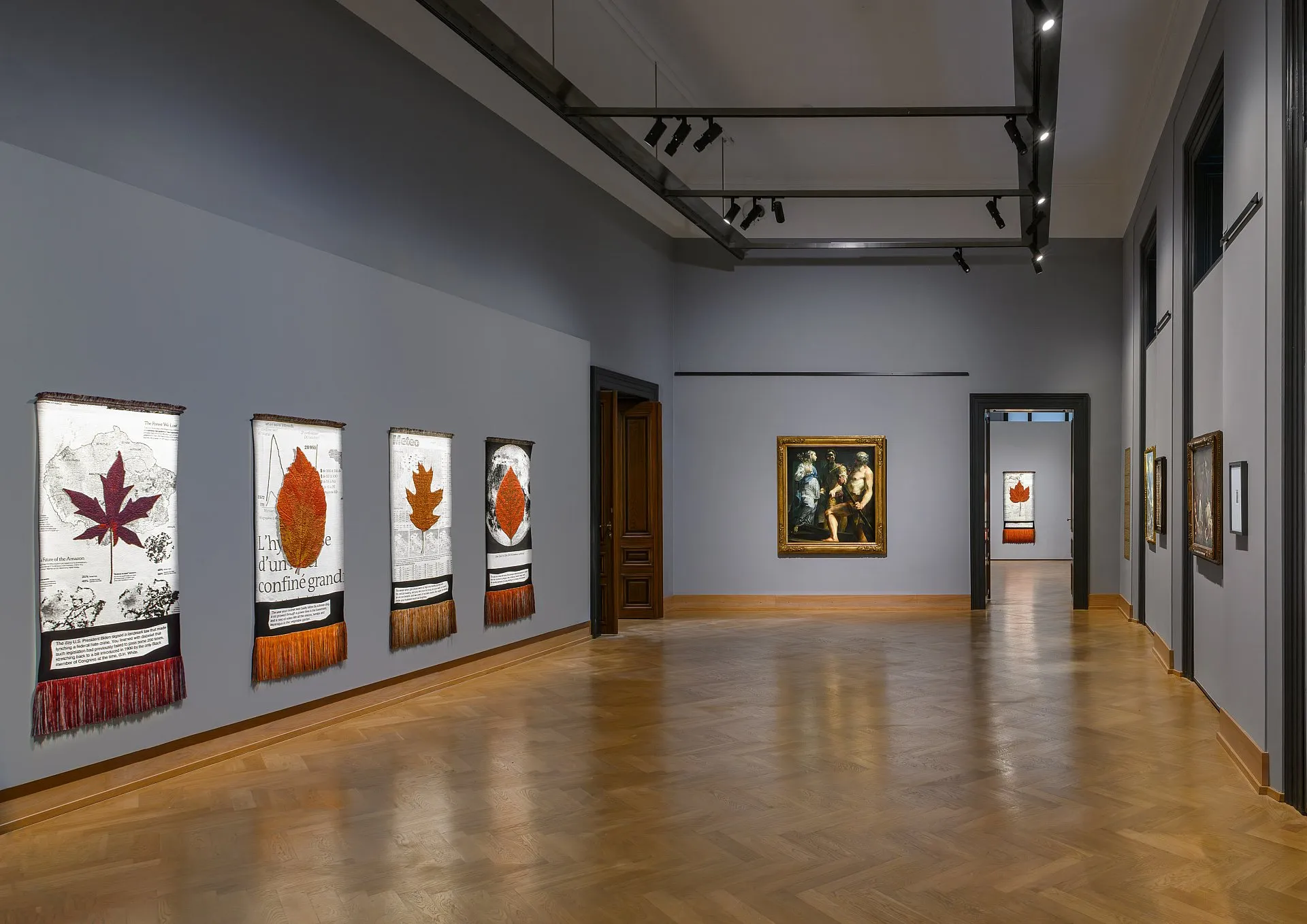 sala galeryjna z dziełami sztuki na jasnoszarych ścianach i drewnianych podłogach