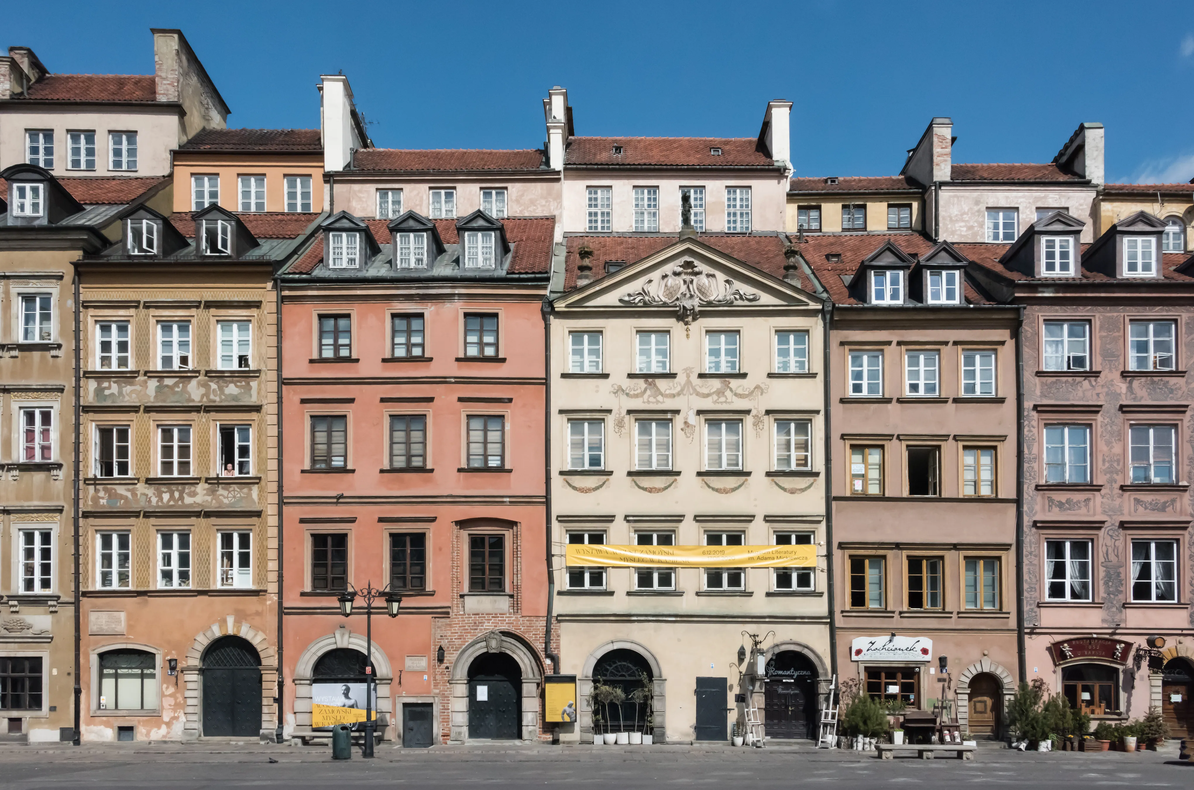 Kolorowe zabytkowe budynki o zróżnicowanych fasadach i dwuspadowych dachach wzdłuż placu miejskiego