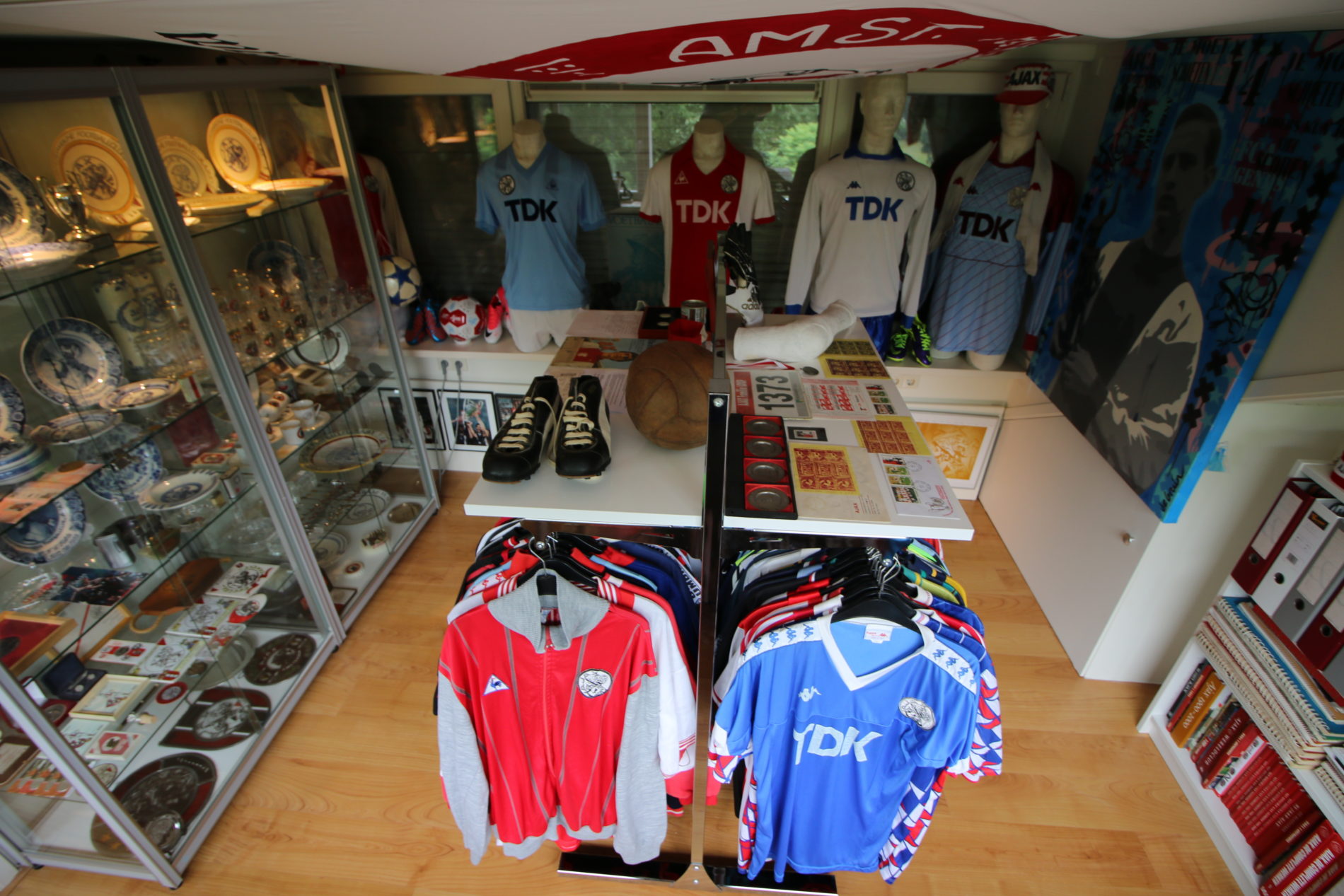 Wystawa koszulek AFC Ajax, trofeów w gablotach i manekinów w historycznych strojach we wnętrzu muzeum