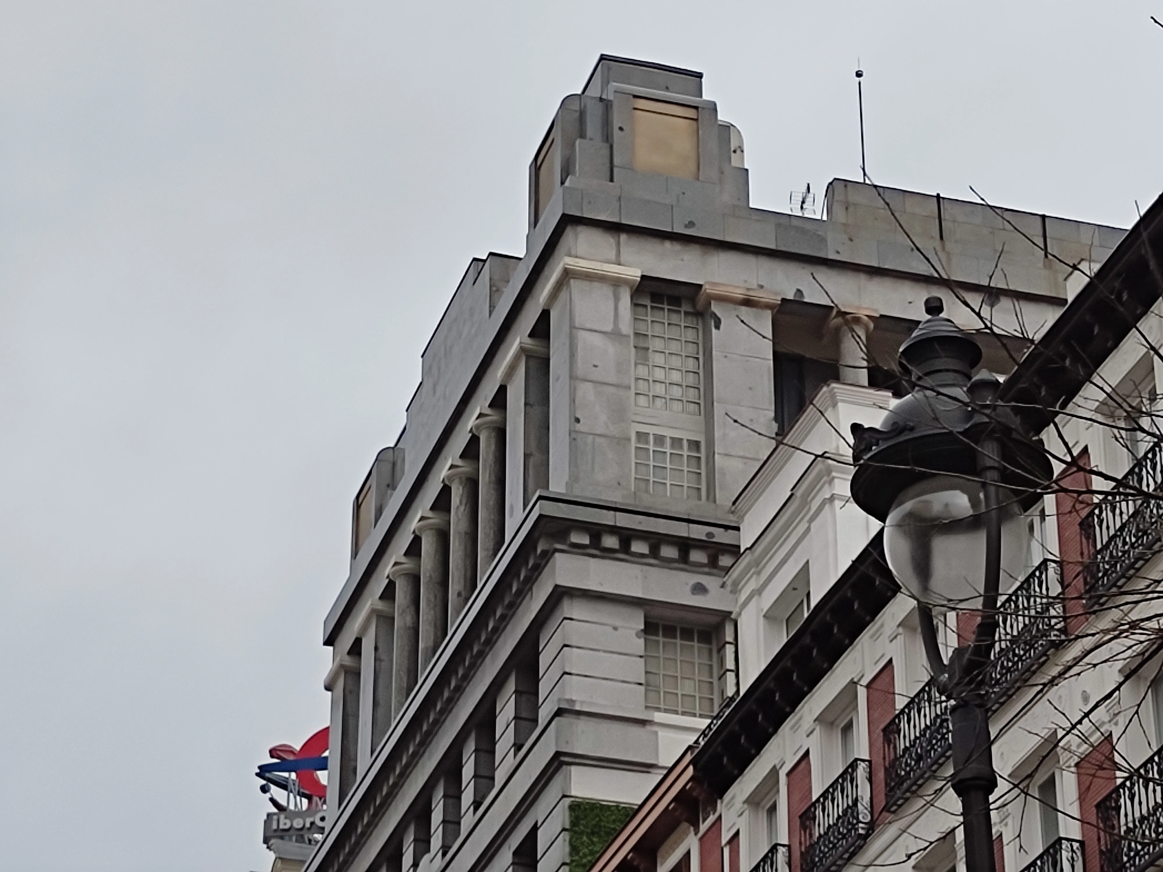 un edificio alto con arquitectura clásica, que presenta columnas, grandes ventanales y una cornisa decorativa, con una farola en primer plano