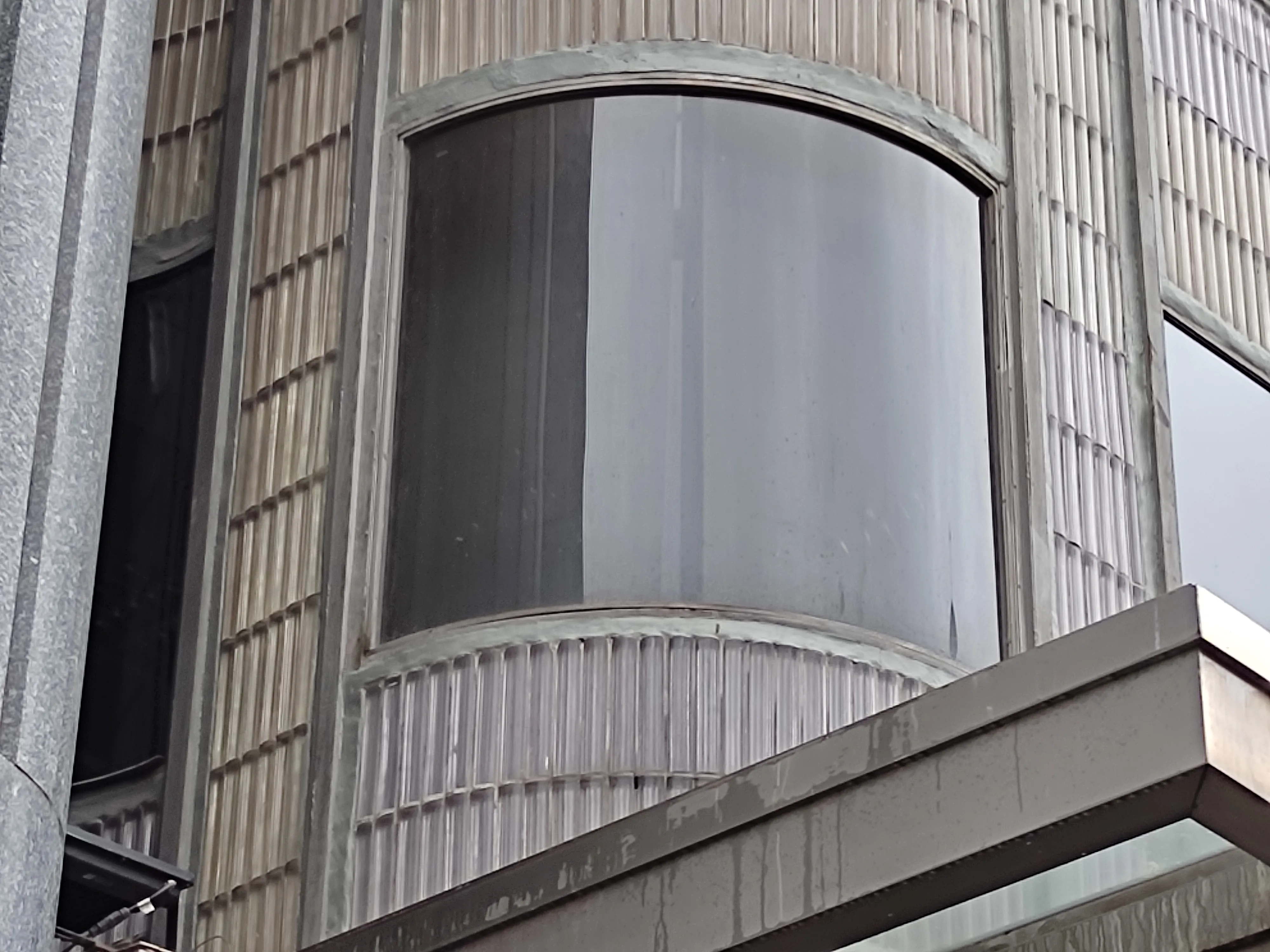 ventana de vidrio curvada en un edificio con paneles texturizados verticales