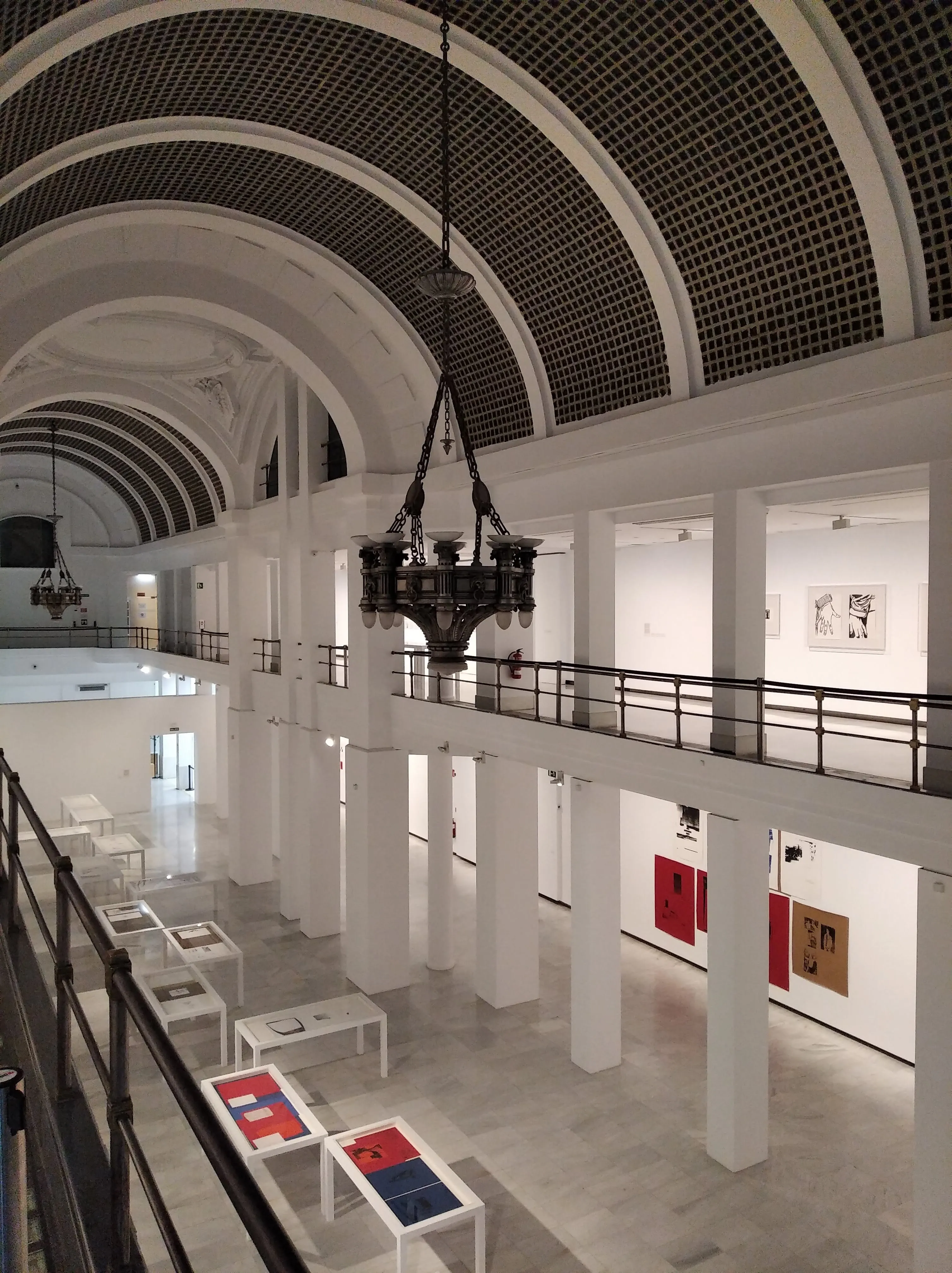 Interior de Sala Alcalá 31 con techos abovedados, columnas blancas e instalaciones artísticas sobre mesas y paredes