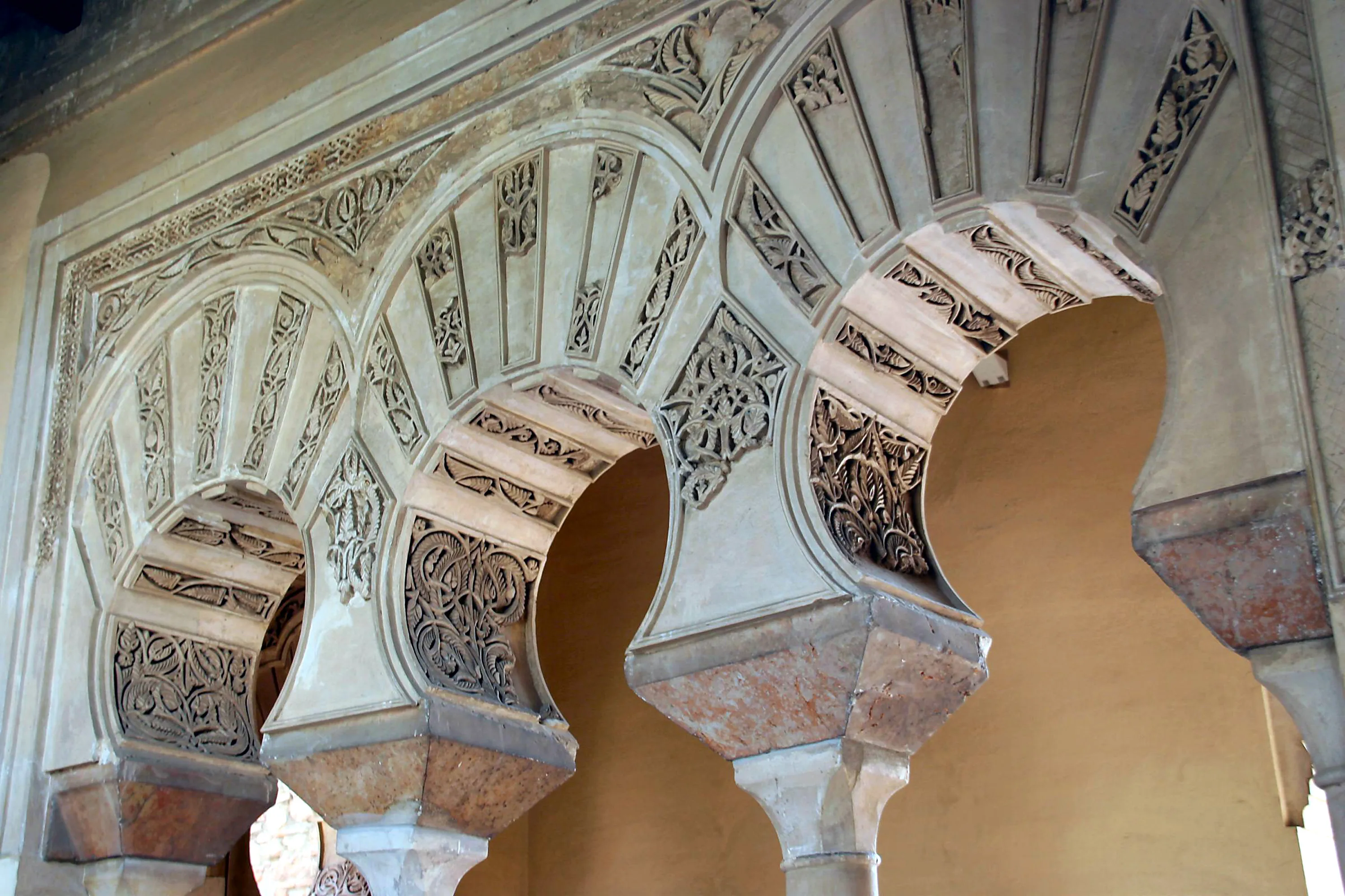 Versierde Moorse veelpas-hoefijzerbogen met ingewikkeld snijwerk in stucwerk en geometrische bloempatronen in de Alcazaba van Málaga