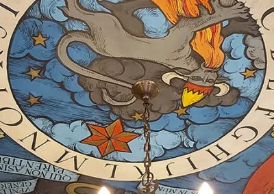 circular mural with alchemical symbol of a griffin, stars, and Latin text