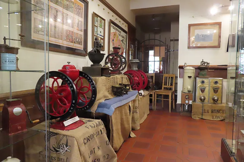 Antique coffee grinders and roasters on display in glass cases inside a museum