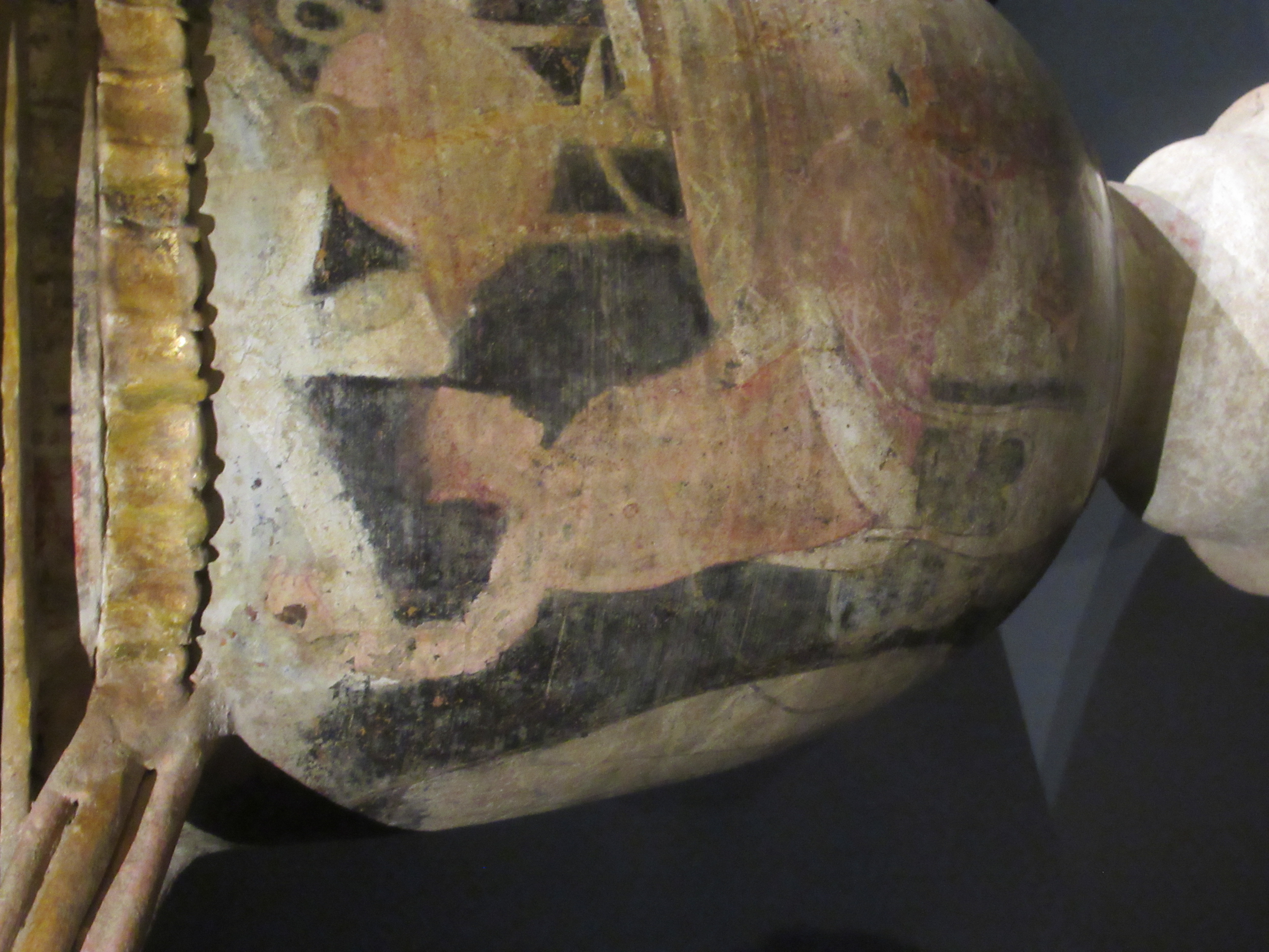 Close-up of an ancient painted pottery vessel showing a human figure and animal motifs on its surface