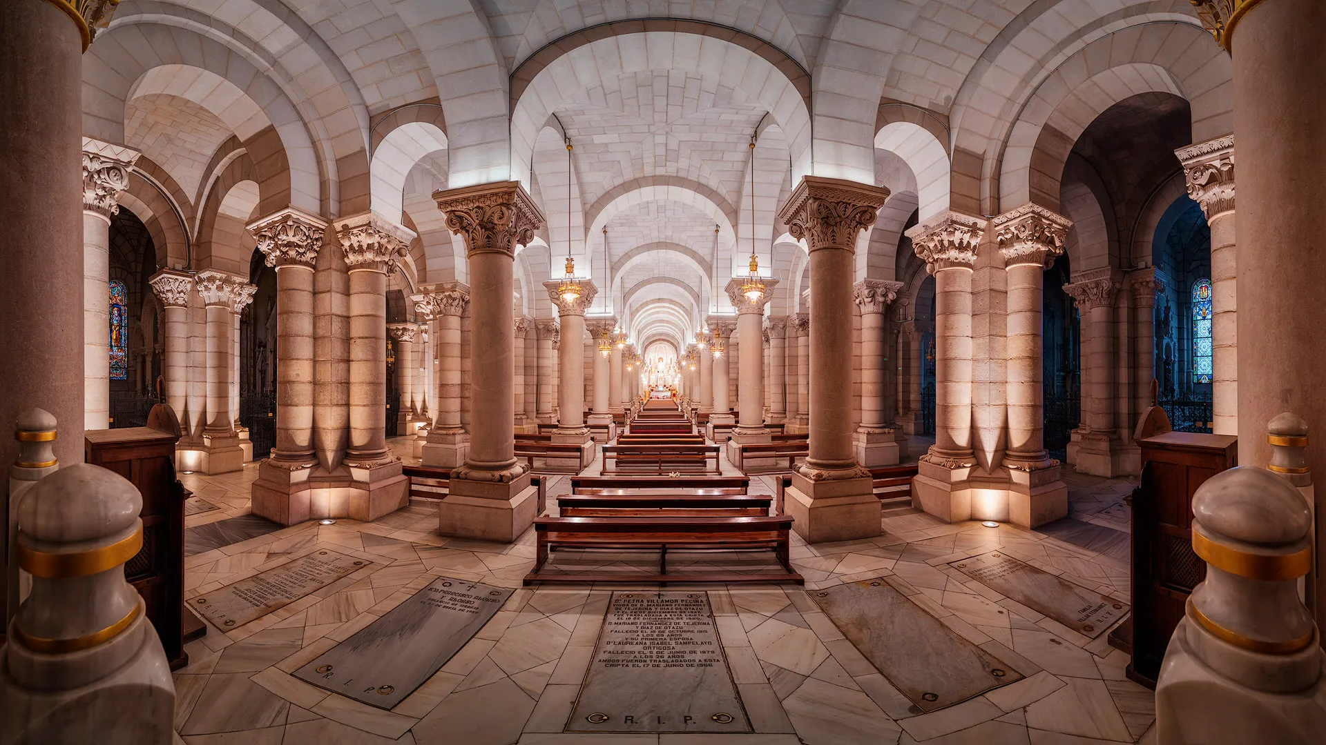 Interior of a cathedral with stone columns, arched ceilings, and wooden pews