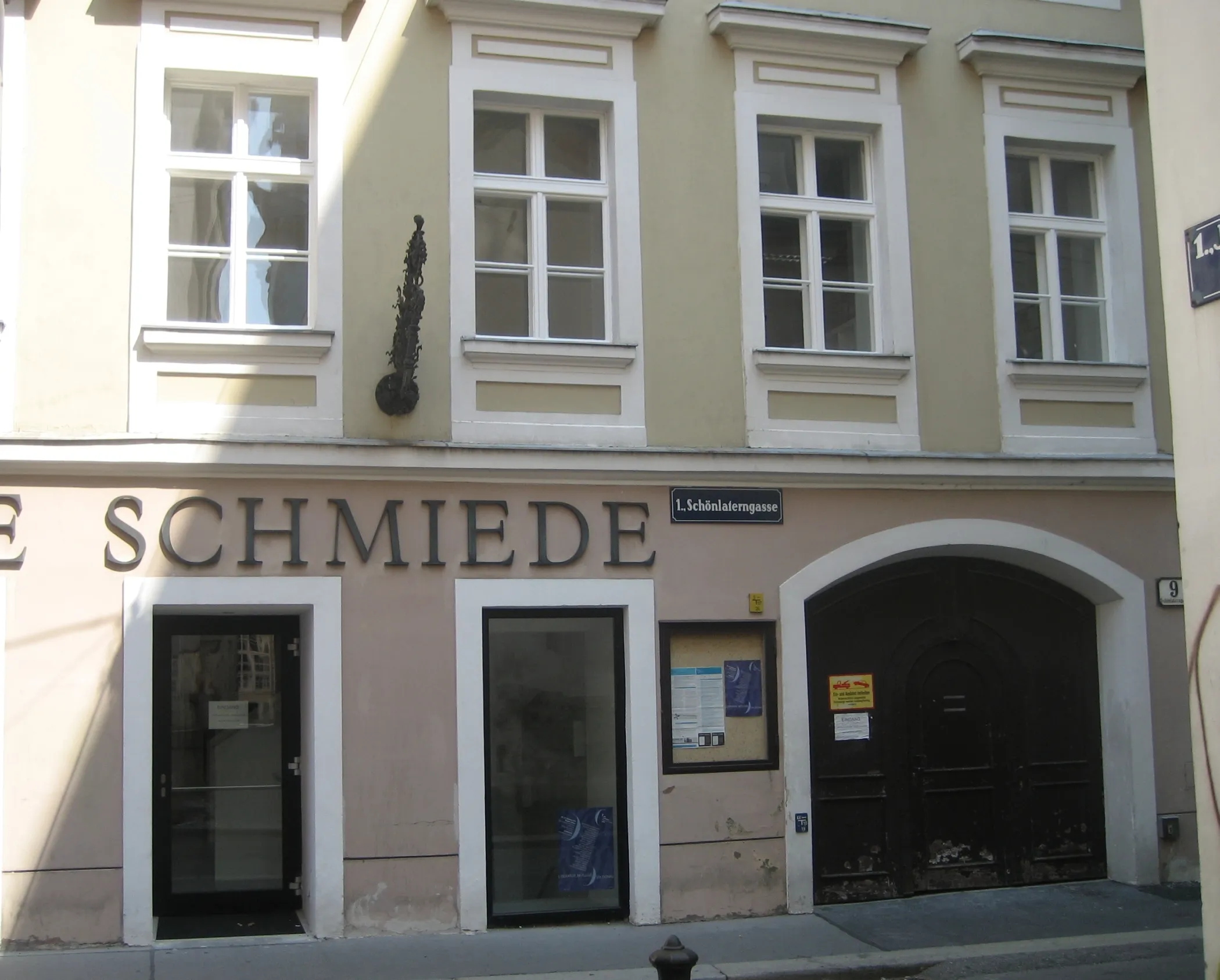 El exterior de Alte Schmiede, un lugar cultural en Viena, con su nombre en la fachada sobre la entrada y un letrero de Schönlaterngasse.