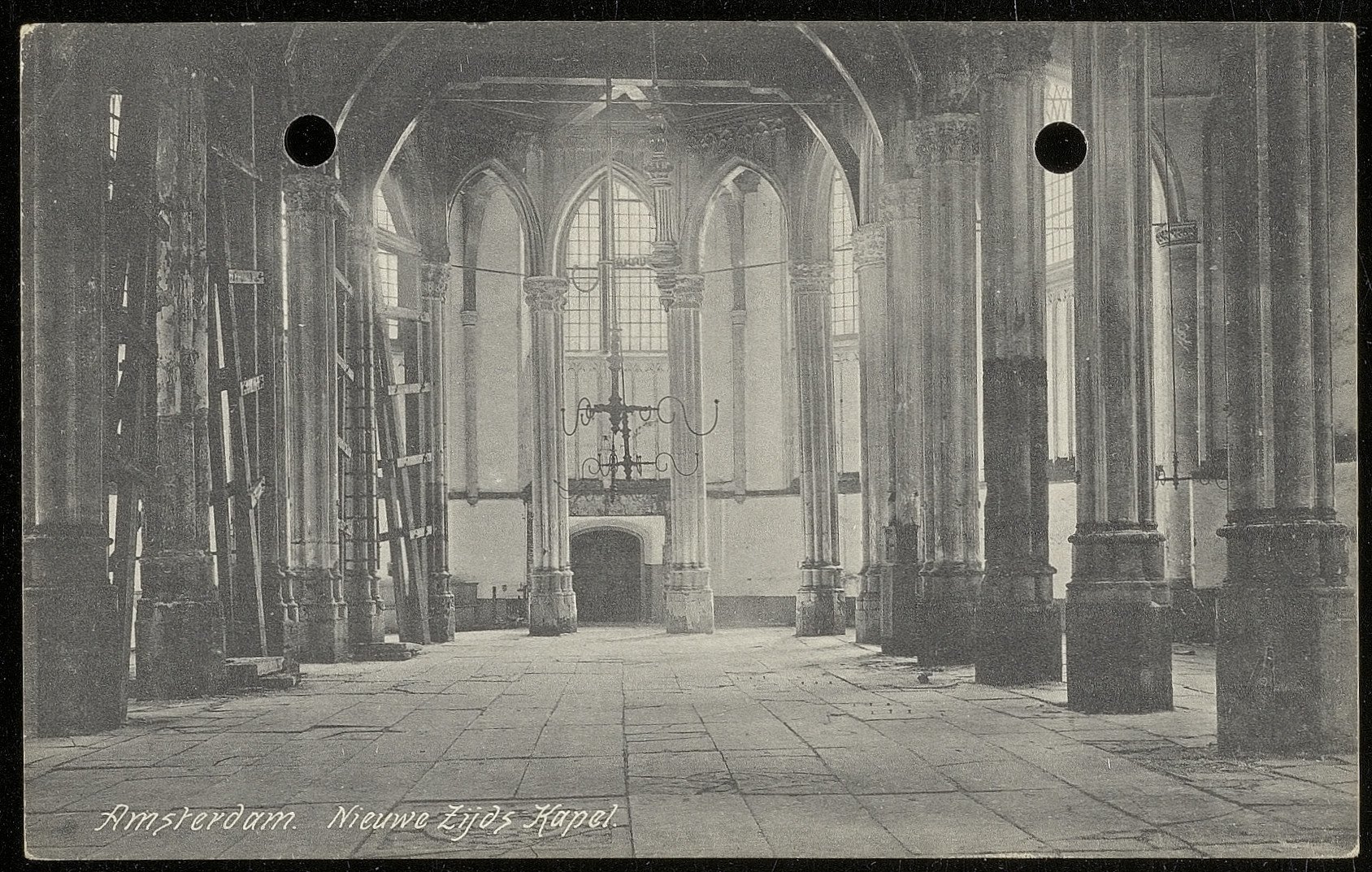 Interior of a historic building with tall stone columns, arched windows, and a vaulted ceiling