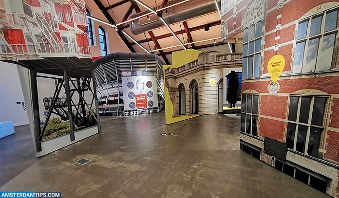 Interior space of Amsterdam in Motion venue featuring large-scale projections of Amsterdam buildings on walls, concrete floor, and exposed industrial ceiling beams