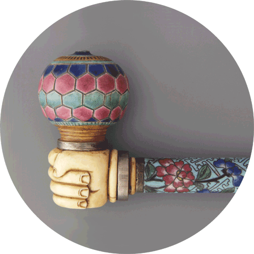 Intrincada pipa de fumar con una cazoleta hexagonal colorida, un agarre tallado y un vástago con estampado floral sobre un fondo neutro.