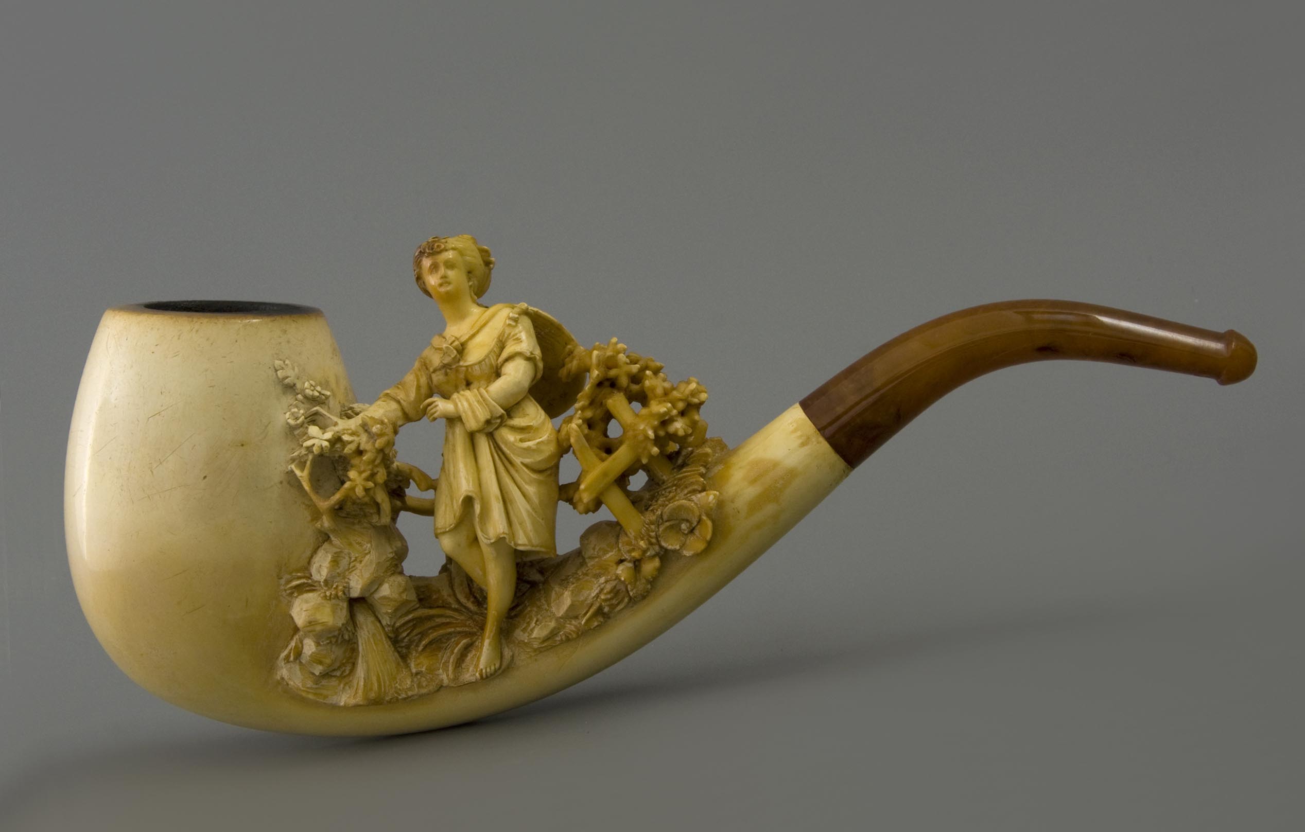 Pipa tallada intrincadamente con una figura de mujer esculpida y detalles florales