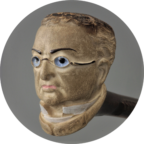 Tazón de pipa tallado que representa una cara con ojos azules, gafas y bigote