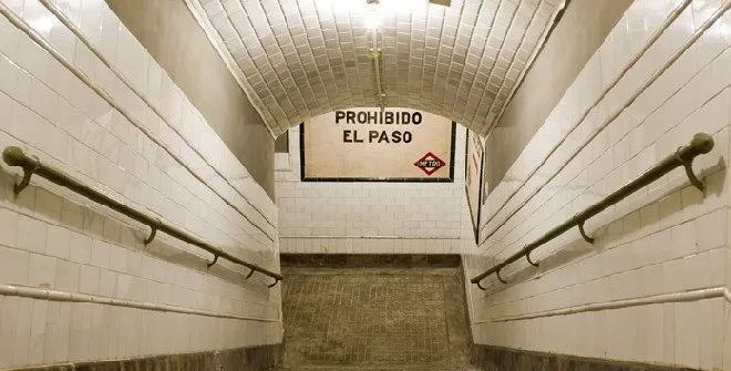 witte betegelde metrohal met gewelfd plafond en een bord met de tekst 'PROHIBIDO EL PASO'