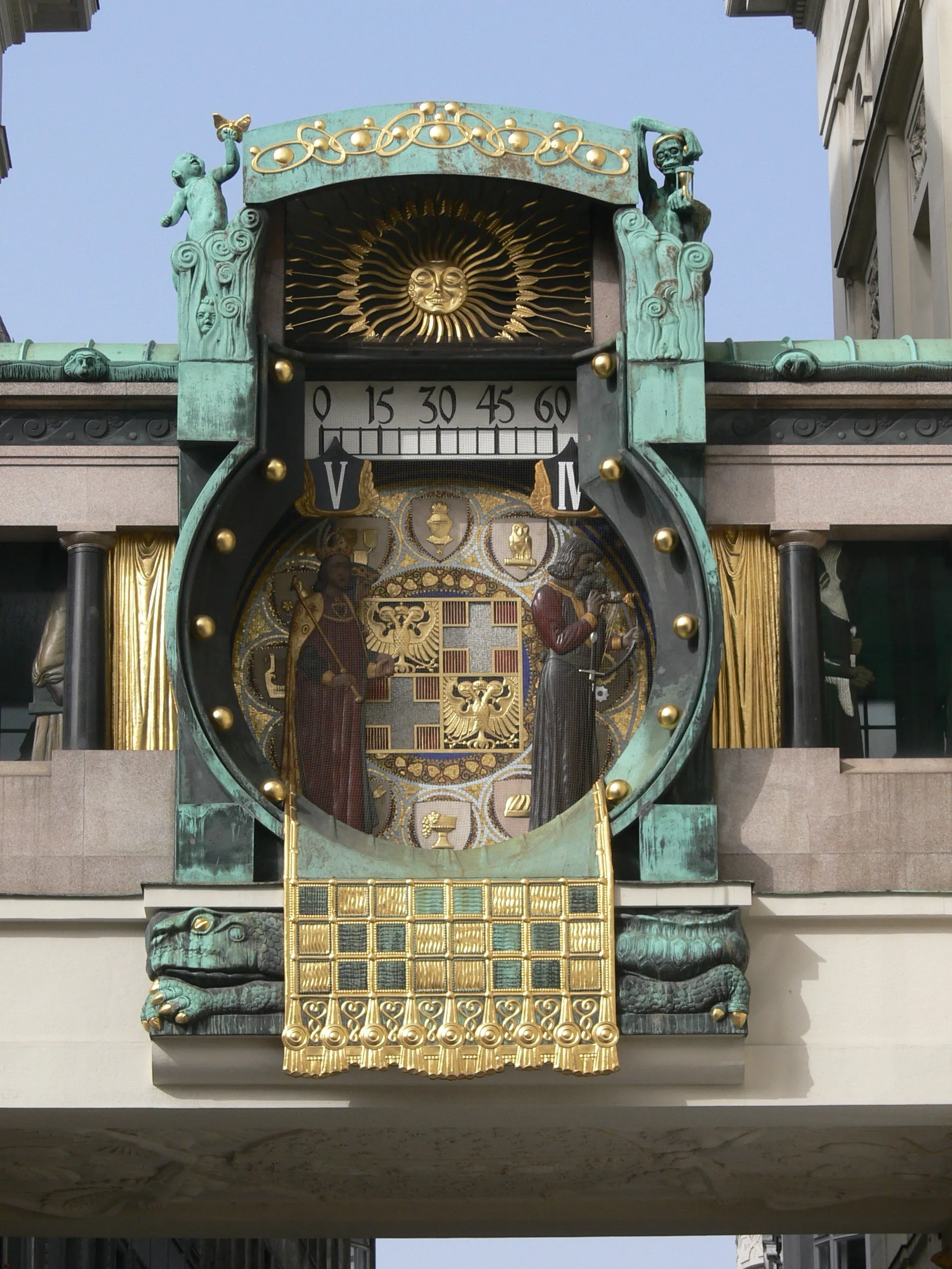 Art Nouveau klok met gouden figuren, zonne motief en sierlijke details op een gebouwgevel