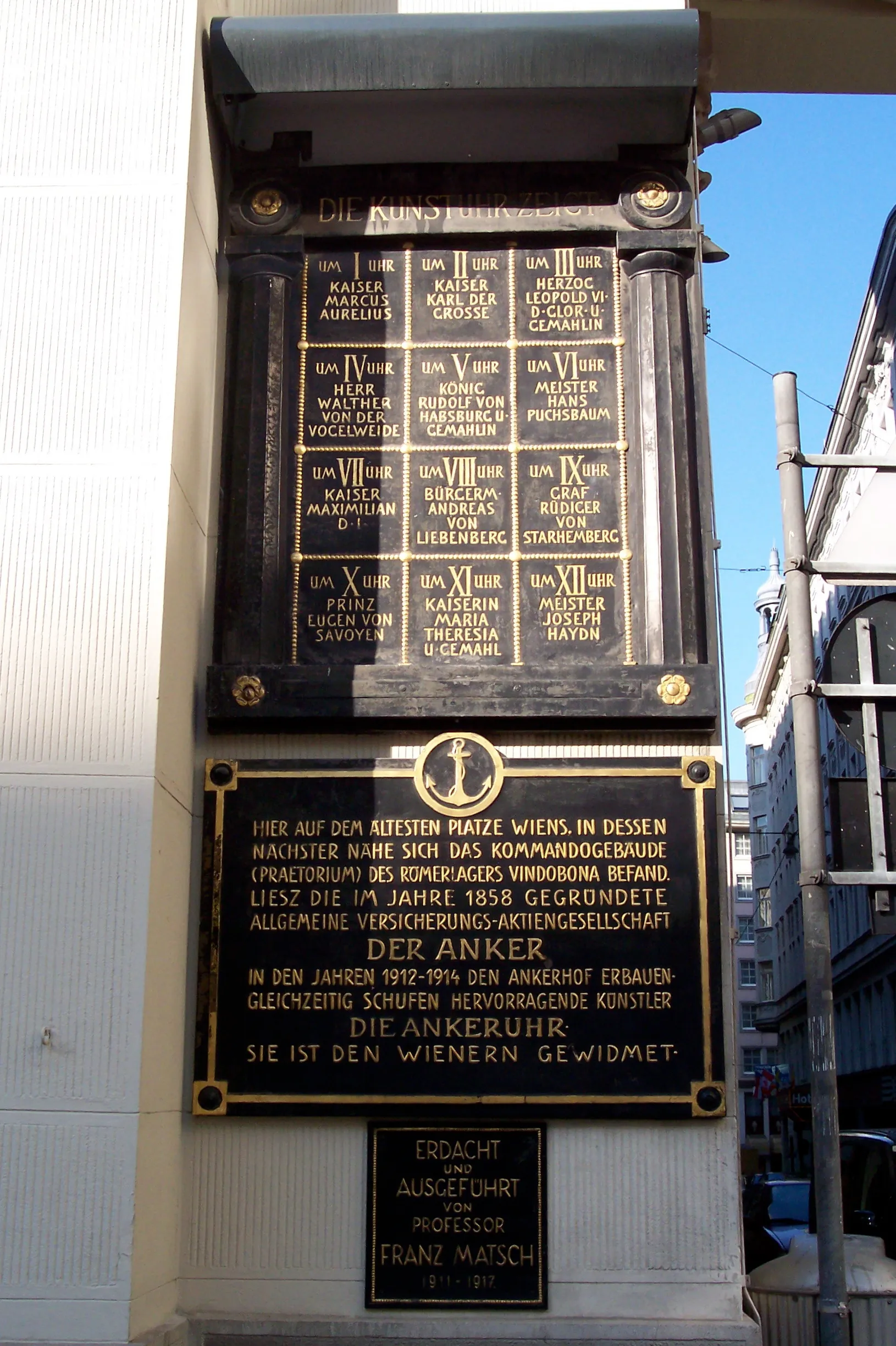 close-up van een zwarte plaquette met gouden letters op de Ankerklok, met historische tekst en het ankersymbool
