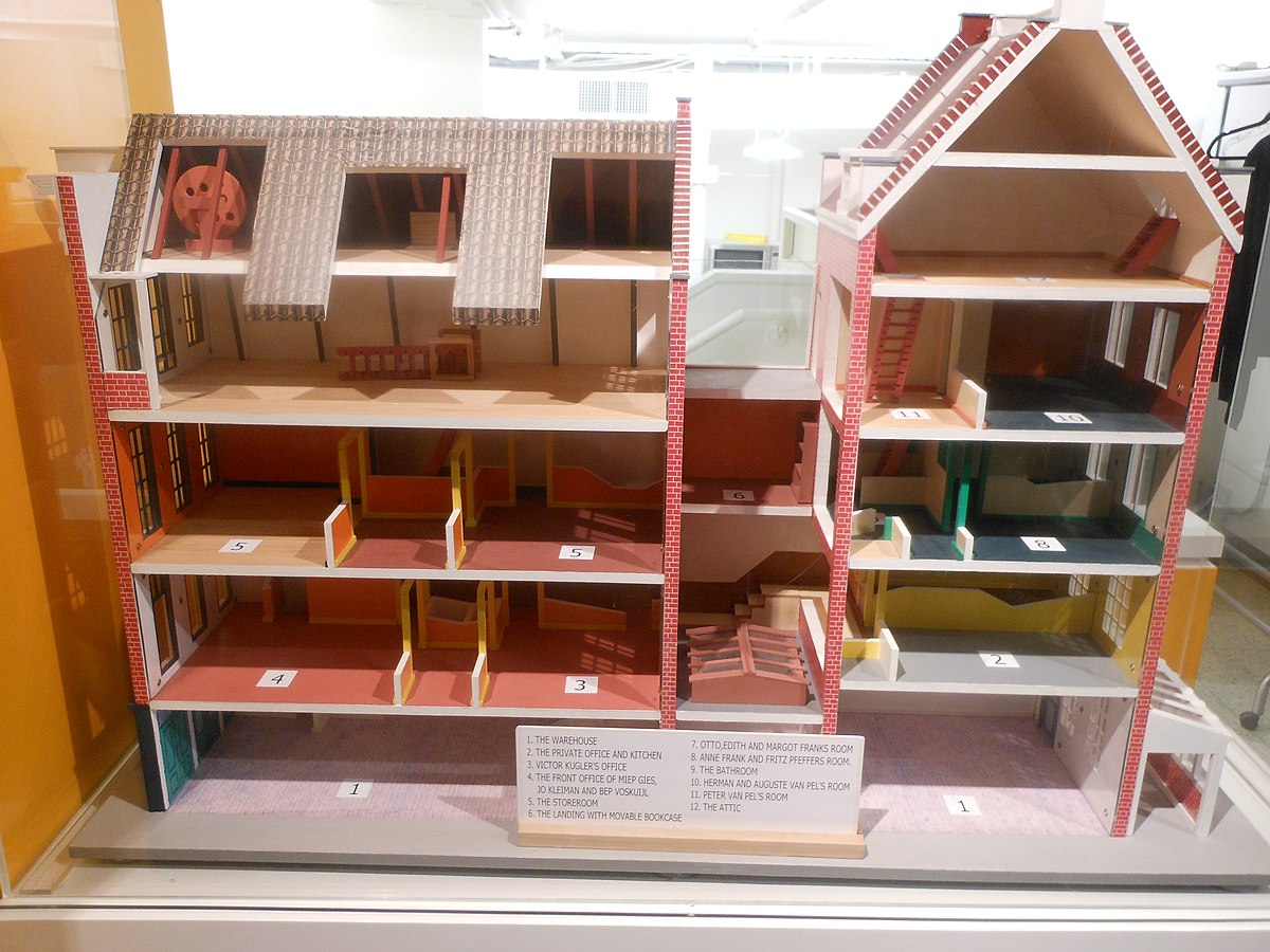 Gedetailleerd architectonisch model van een meerlaags gebouw met een doorsnedevisualisatie die de binnenruimtes en indeling toont, tentoongesteld in een vitrine met een informatiebordje.