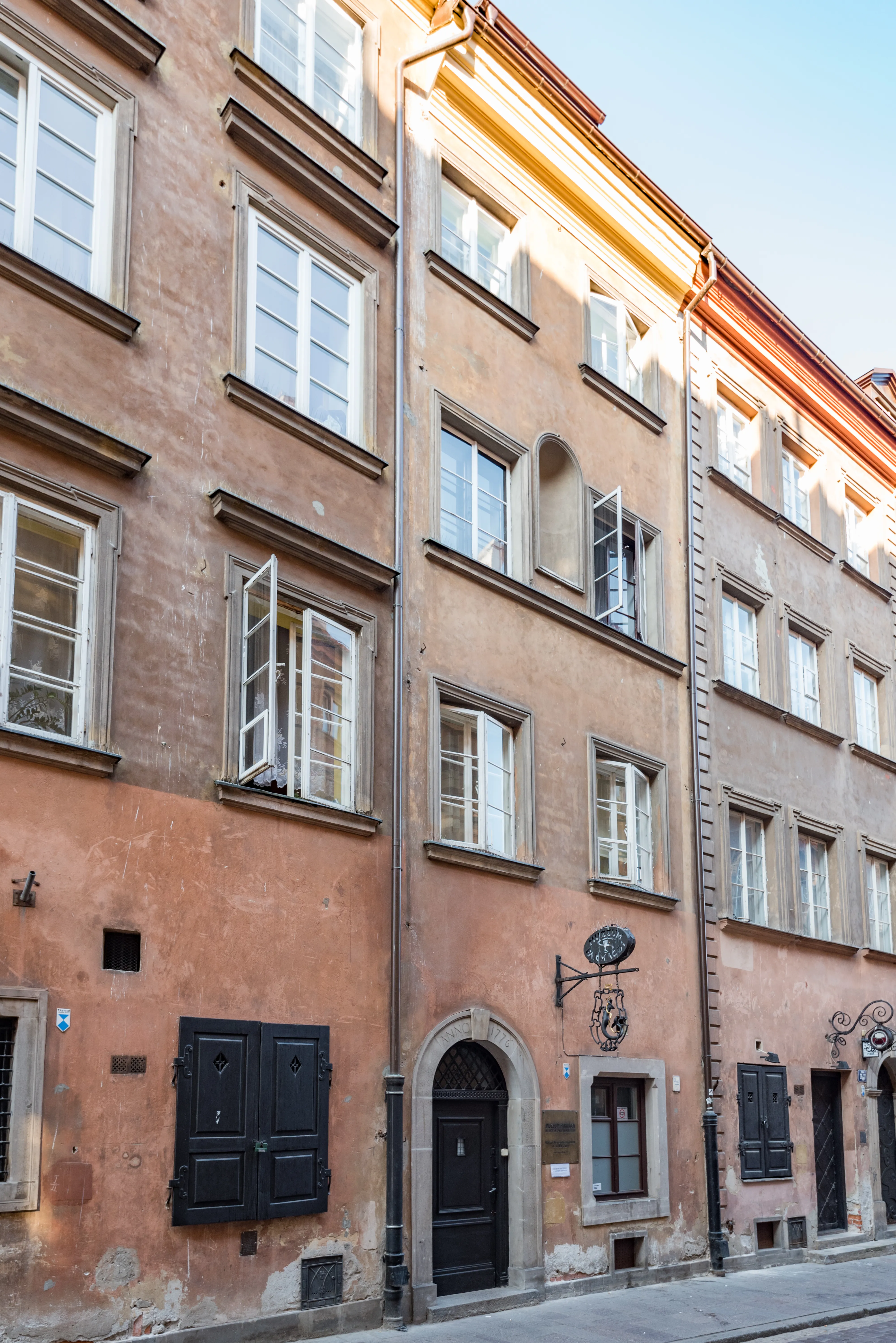 Een historisch gebouw met een terracotta gevel, boogvormige ingang en traditionele ramen in Warschau