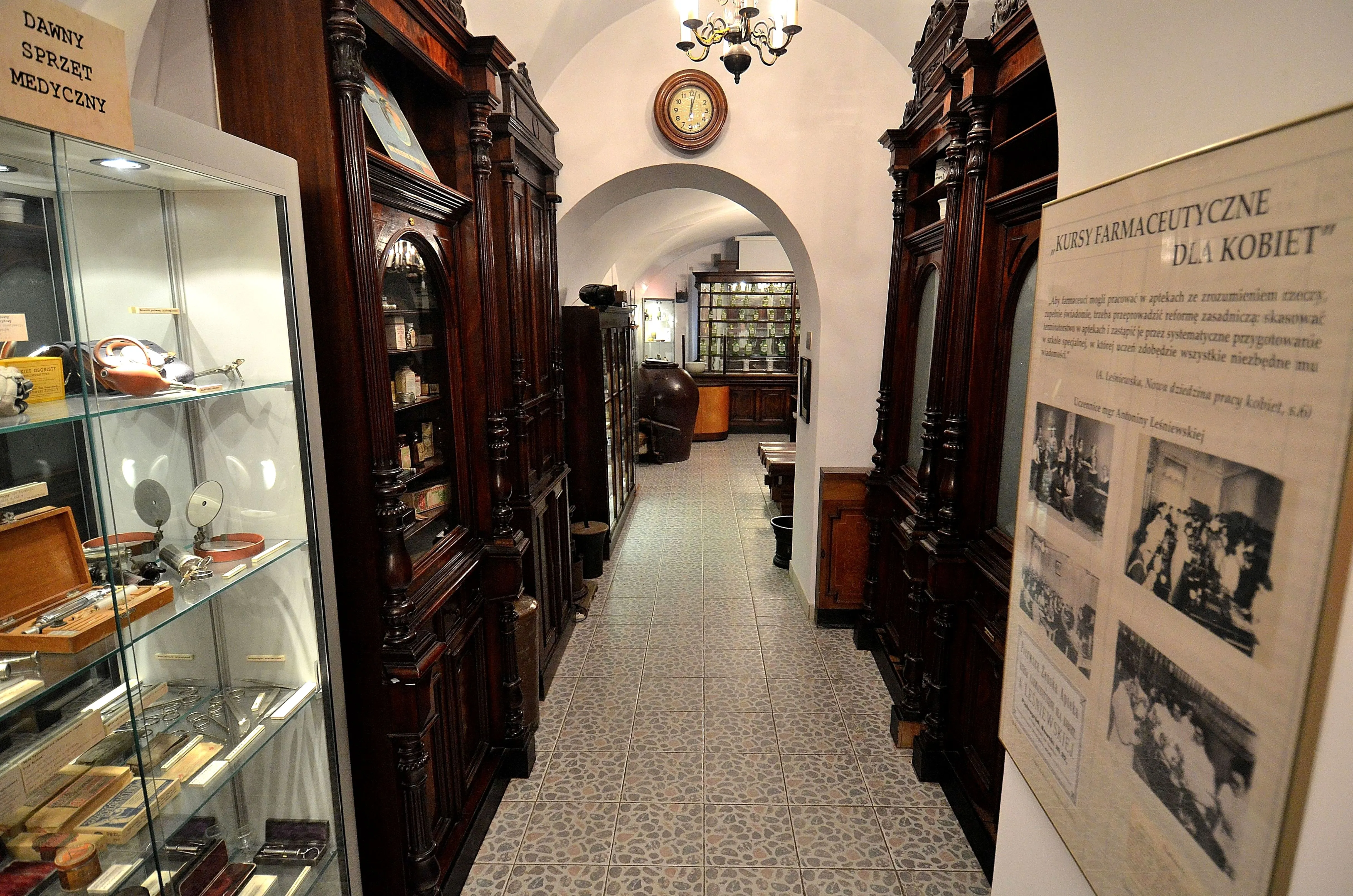 Interieur hal van een museum met donkerhouten kasten, glazen vitrines en een groot informatiepaneel aan de muur.