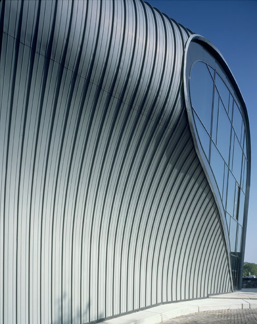 Curved metallic facade with vertical strips and large oval window of the Amsterdam Centre for Architecture (ARCAM) building