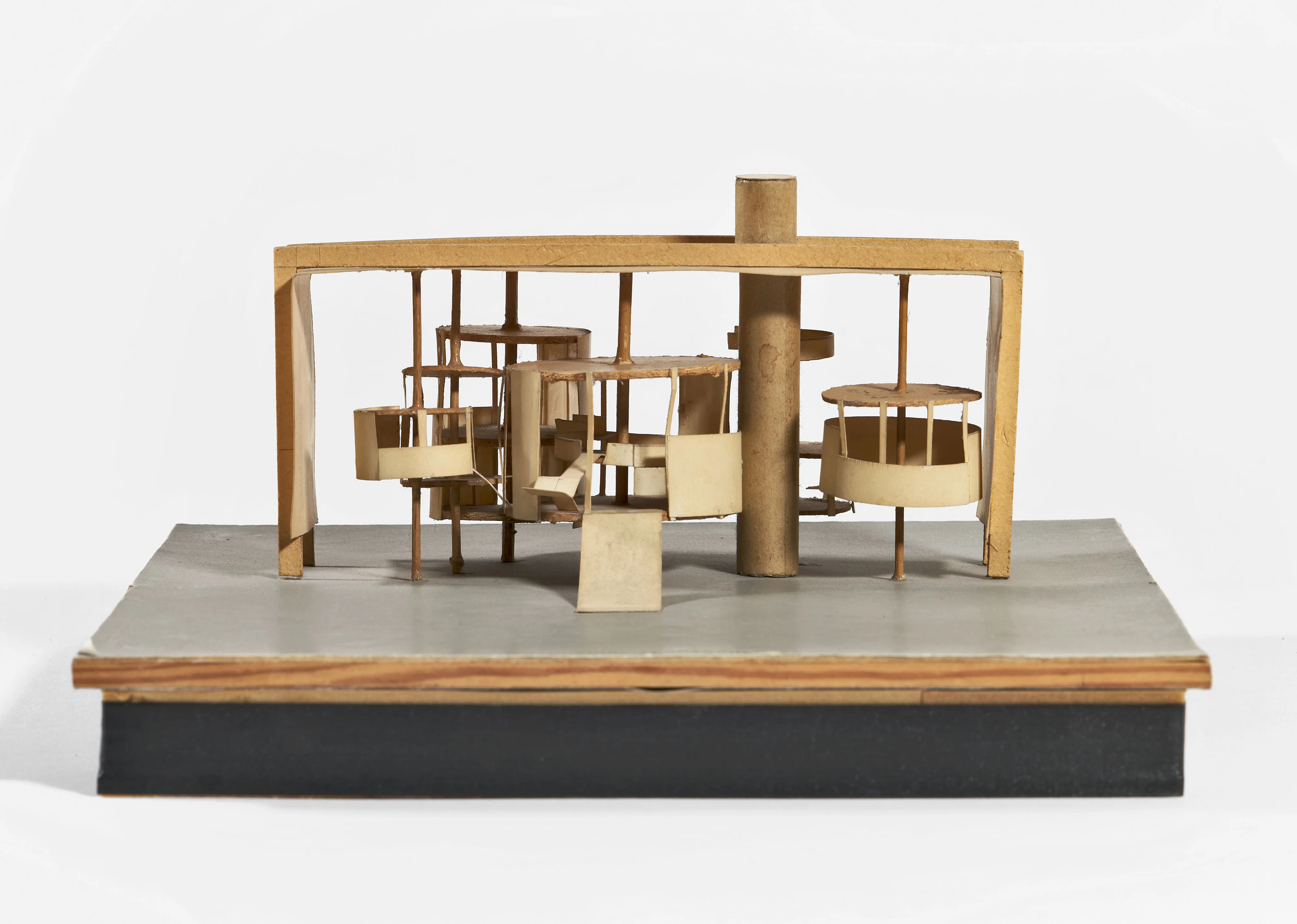 Wooden architectural model with circular and rectangular components on a gray base