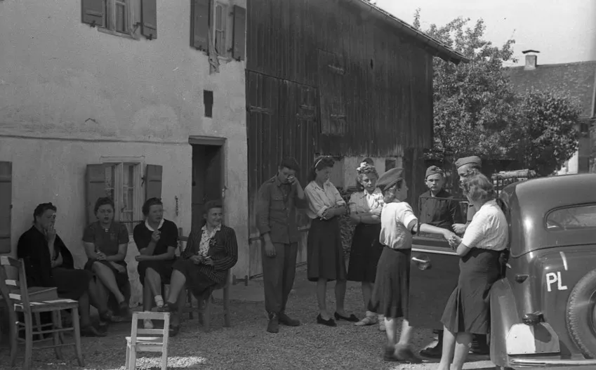 a group of people gathered outside a building with a vintage car