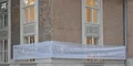 white banner draped across windows of a brick building