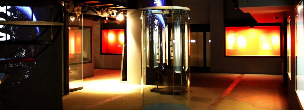 moderne museuminterieur met glazen lift, verlichte displaypanelen en warme verlichting