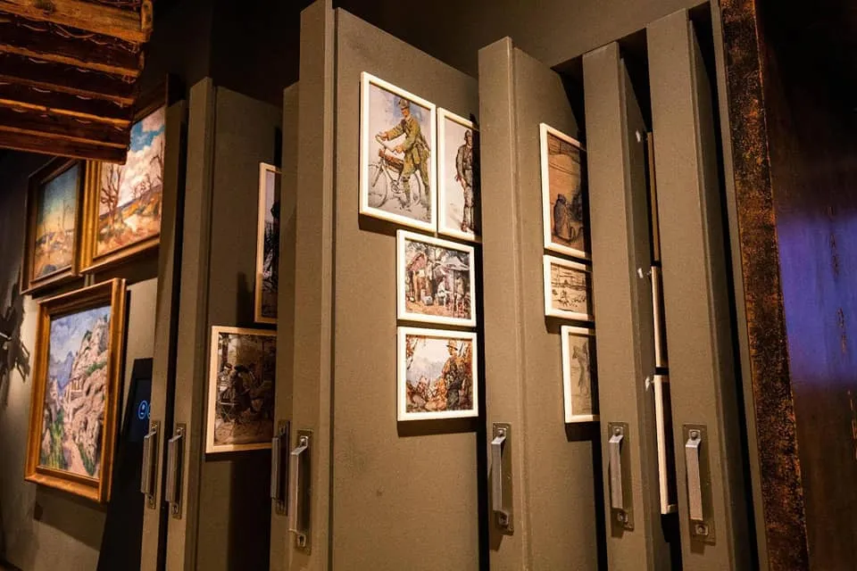 historische schilderijen en illustraties tentoongesteld op donkere muren in een museumgalerij