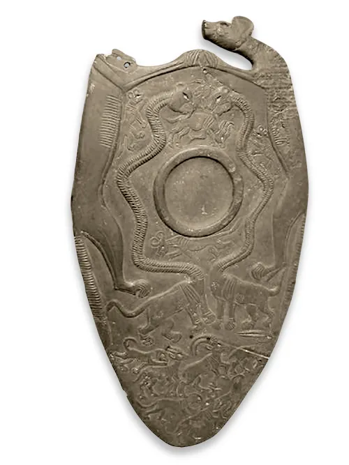 Tarcza ceremonialna z kamienia w kształcie palety z Hierakonpolis, z wyrzeźbionymi splecionymi wężami, postaciami zwierząt i centralnym kolistym wgłębieniem, sfotografowana na białym tle.
