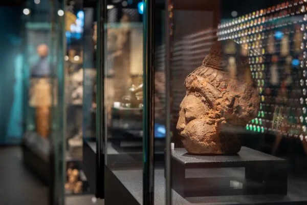 Stenen sculptuur tentoongesteld in een glazen vitrine in een museumgalerij