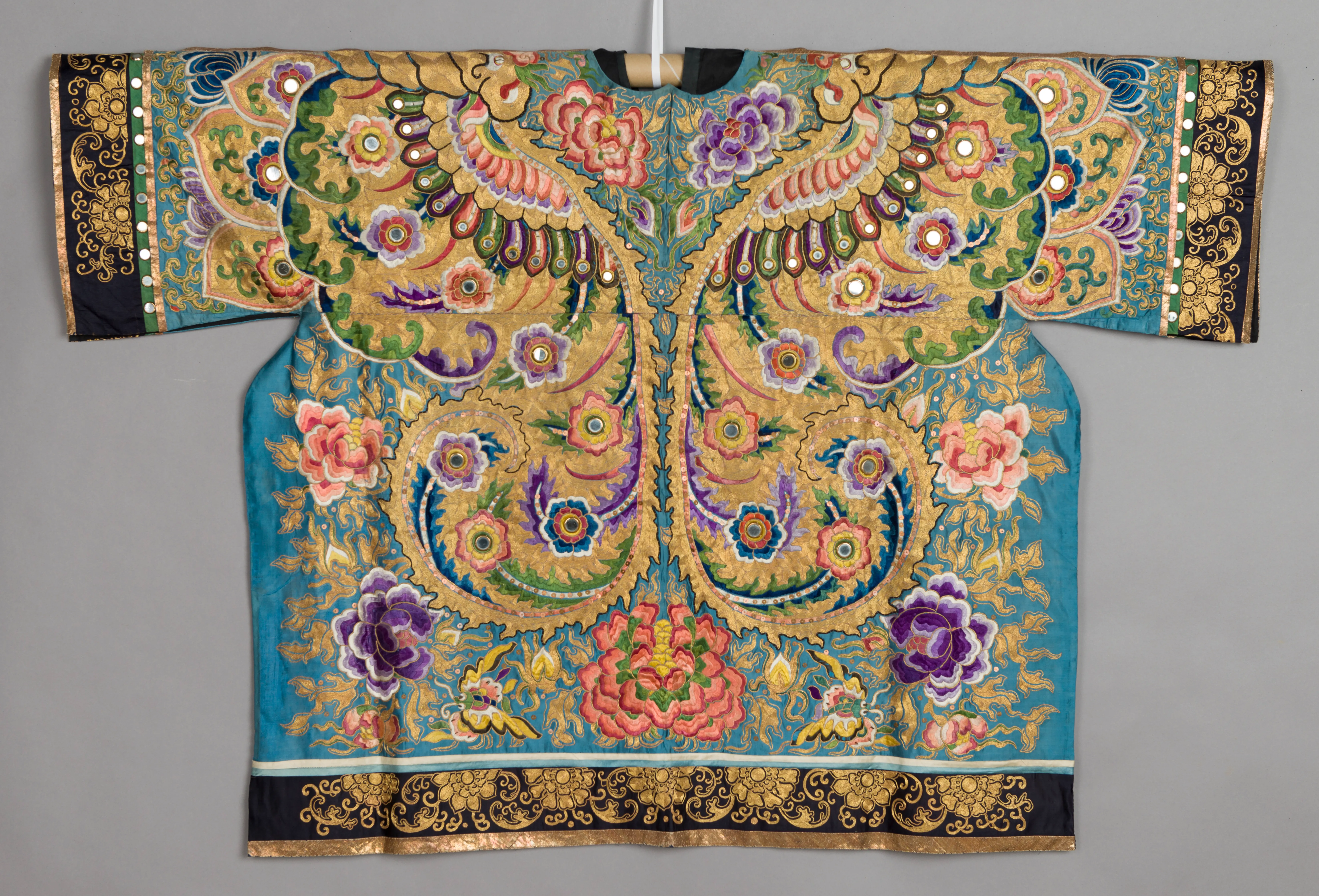Traje teatral tradicional chino con elaborados bordados de flores y pavos reales sobre tela turquesa