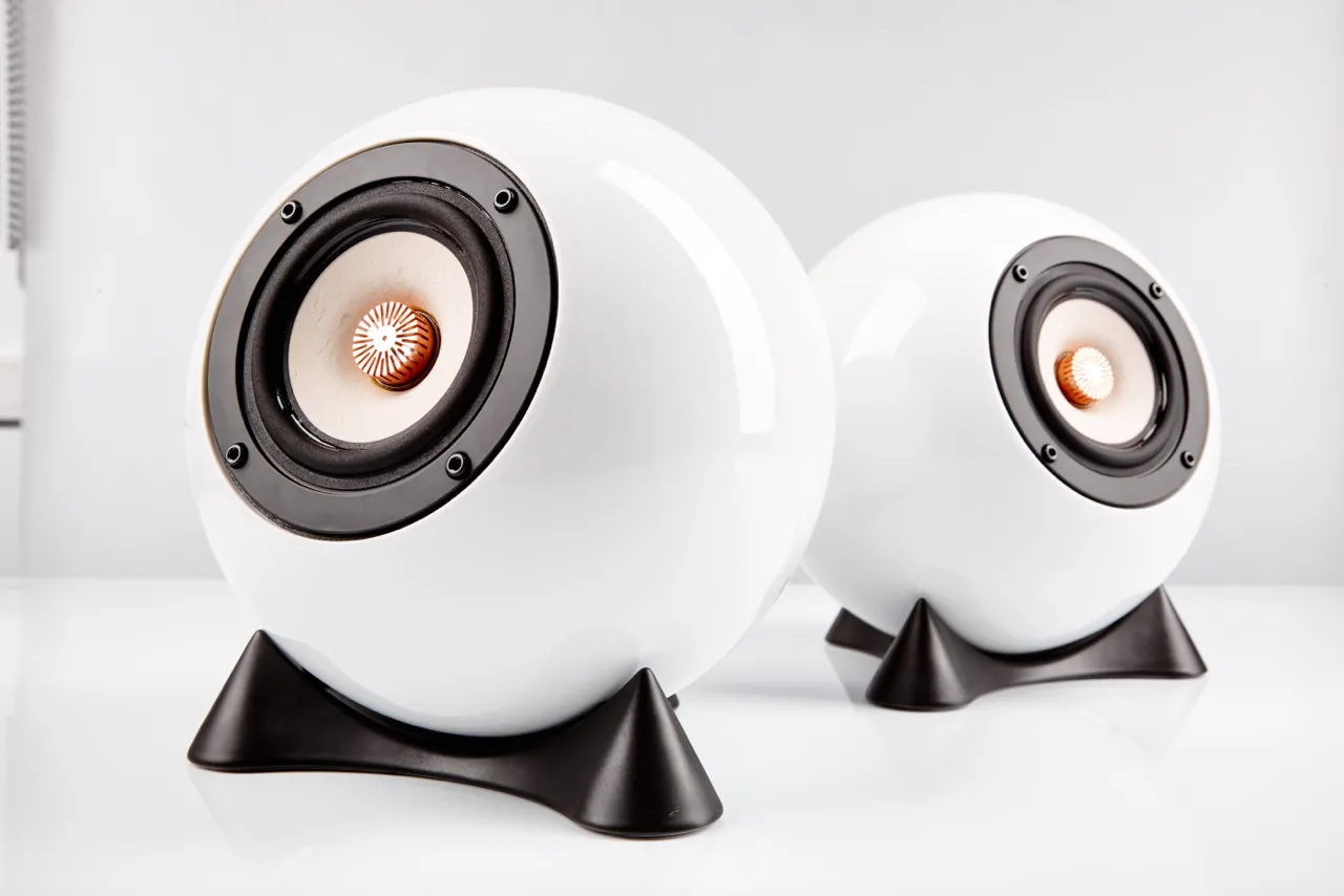Dos altavoces esféricos blancos con bases negras sobre una superficie blanca