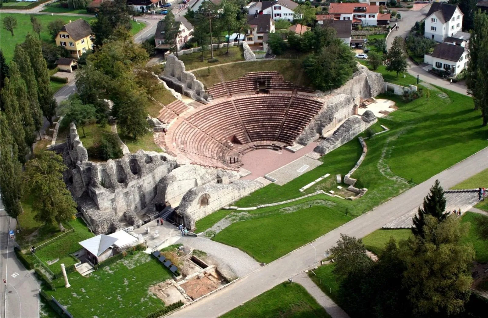 Luchtfoto van de ruïnes van het Romeinse amfitheater in Augusta Raurica, omringd door groene gazons en bomen