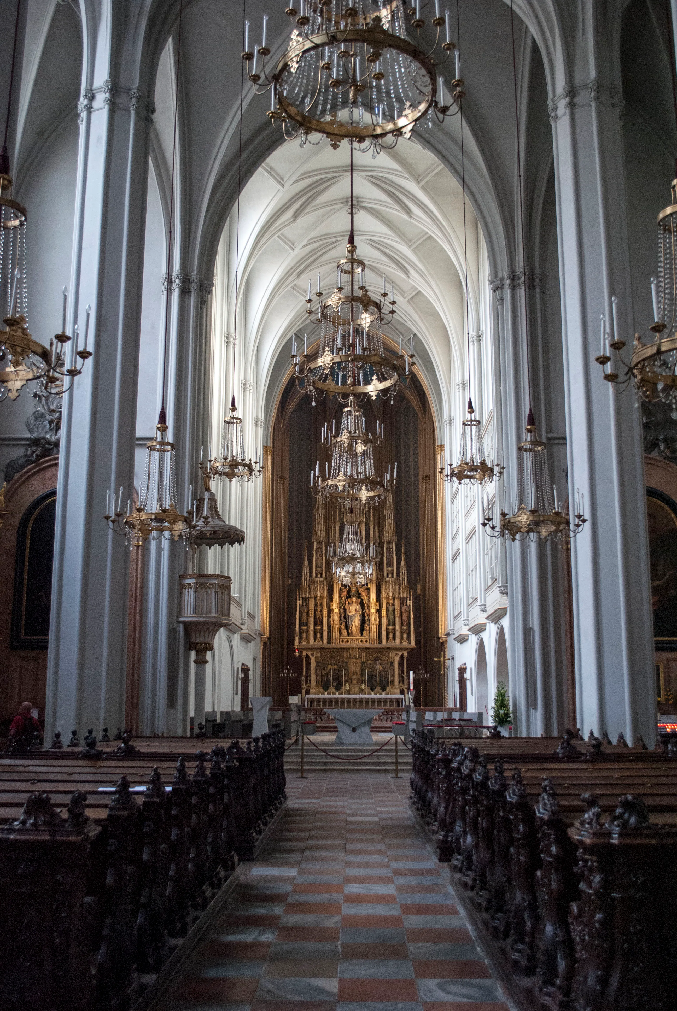 Interior view of the Church of the Augustinian Friars with high white columns, arched ceilings, chandeliers, and a central altar