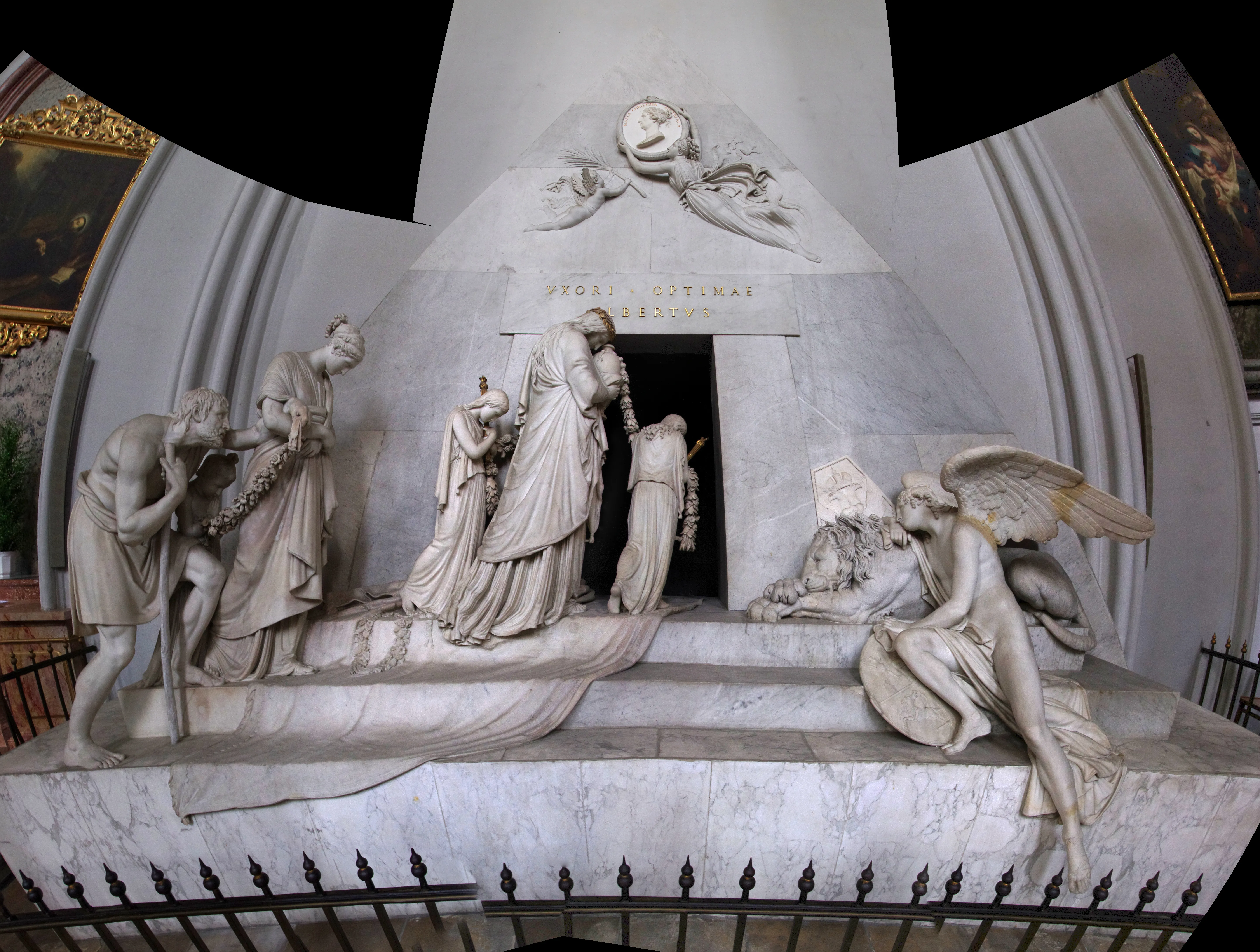 Marble tomb monument with sculpted figures of mourners and angels in a church interior