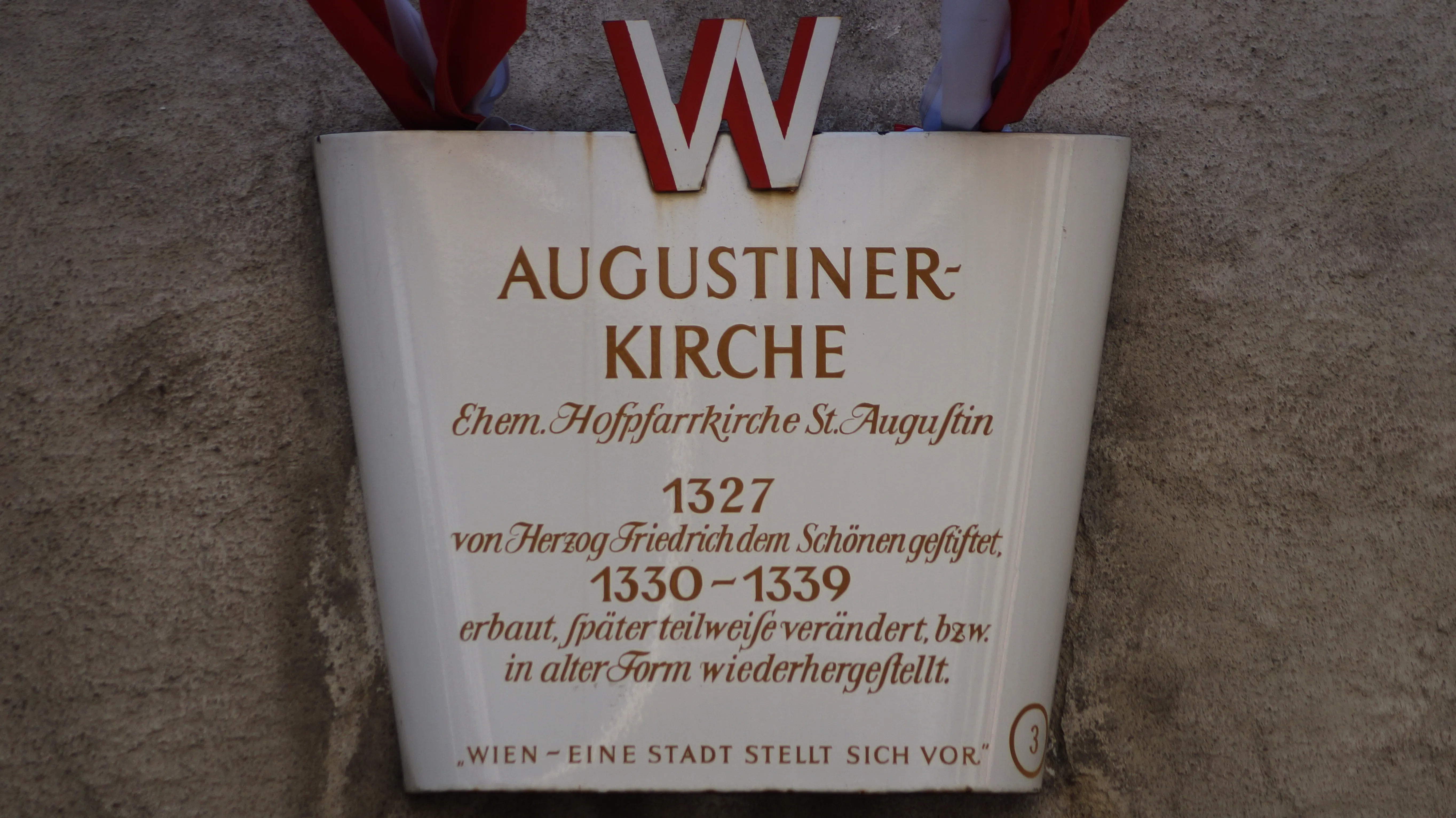 plaque with text AUGUSTINER-KIRCHE and historical information on a stone wall
