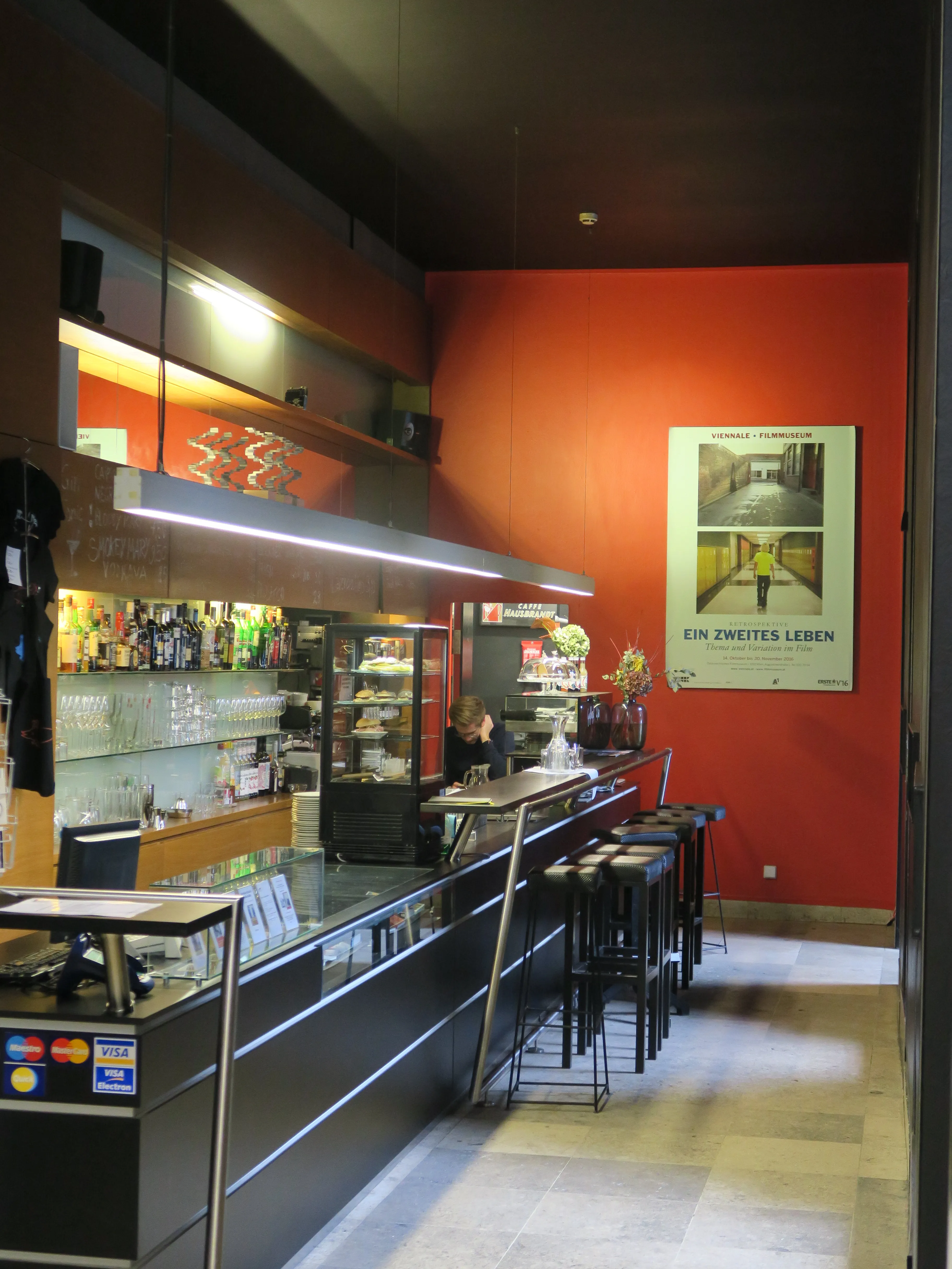 Interior of the Austrian Film Museum with a bar, red wall, and film poster