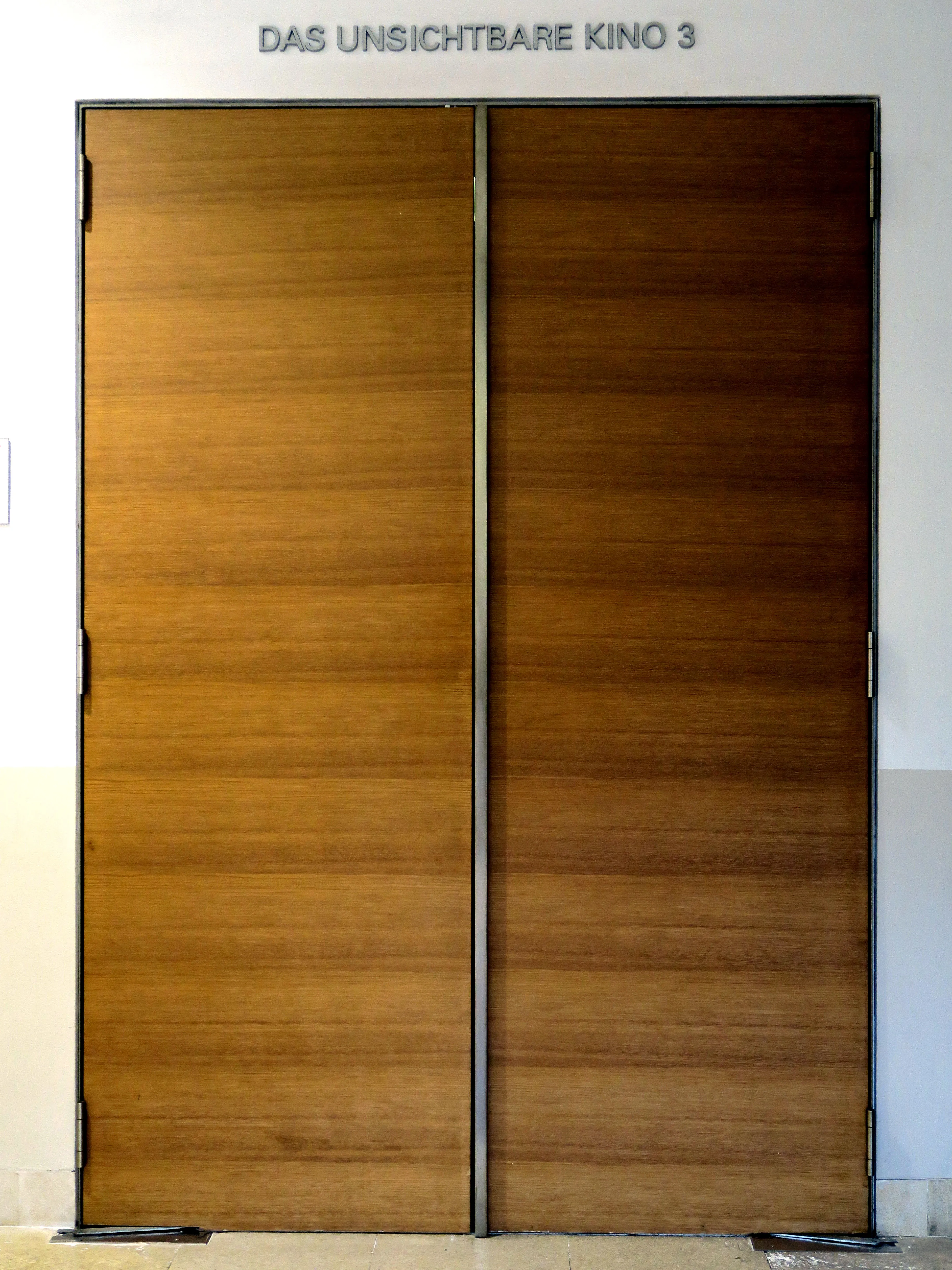 wooden double doors with a sign above reading DAS UNSICHTBARE KINO 3