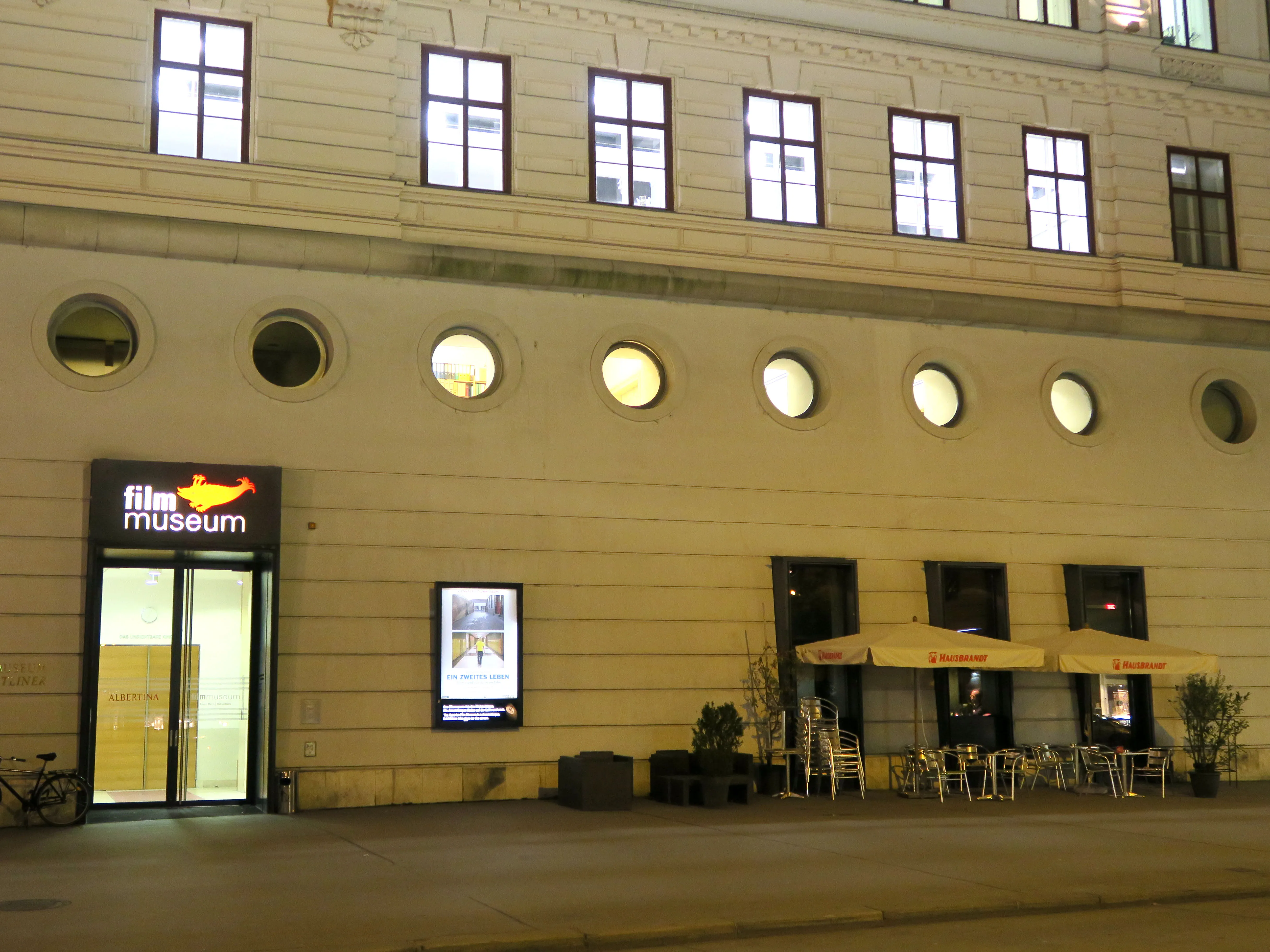Exterior of the Austrian Film Museum at night with a lit sign and circular windows
