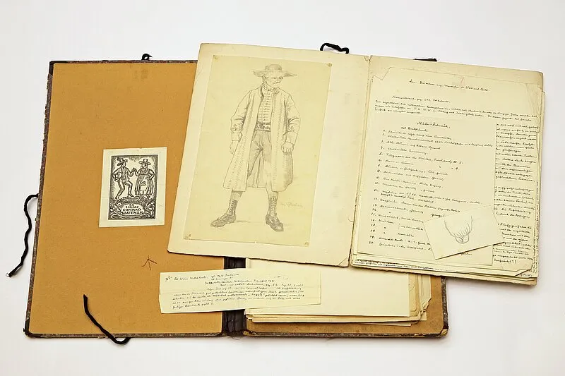 Álbum de archivo abierto con un boceto de una persona con ropa tradicional, texto escrito a mano y una pequeña ilustración impresa en papel envejecido
