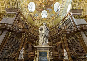 interior de la Biblioteca Nacional de Austria con una estatua central y estanterías doradas