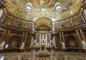 Interior de la Biblioteca Nacional de Austria con techo dorado ornamentado, estanterías y estatuas