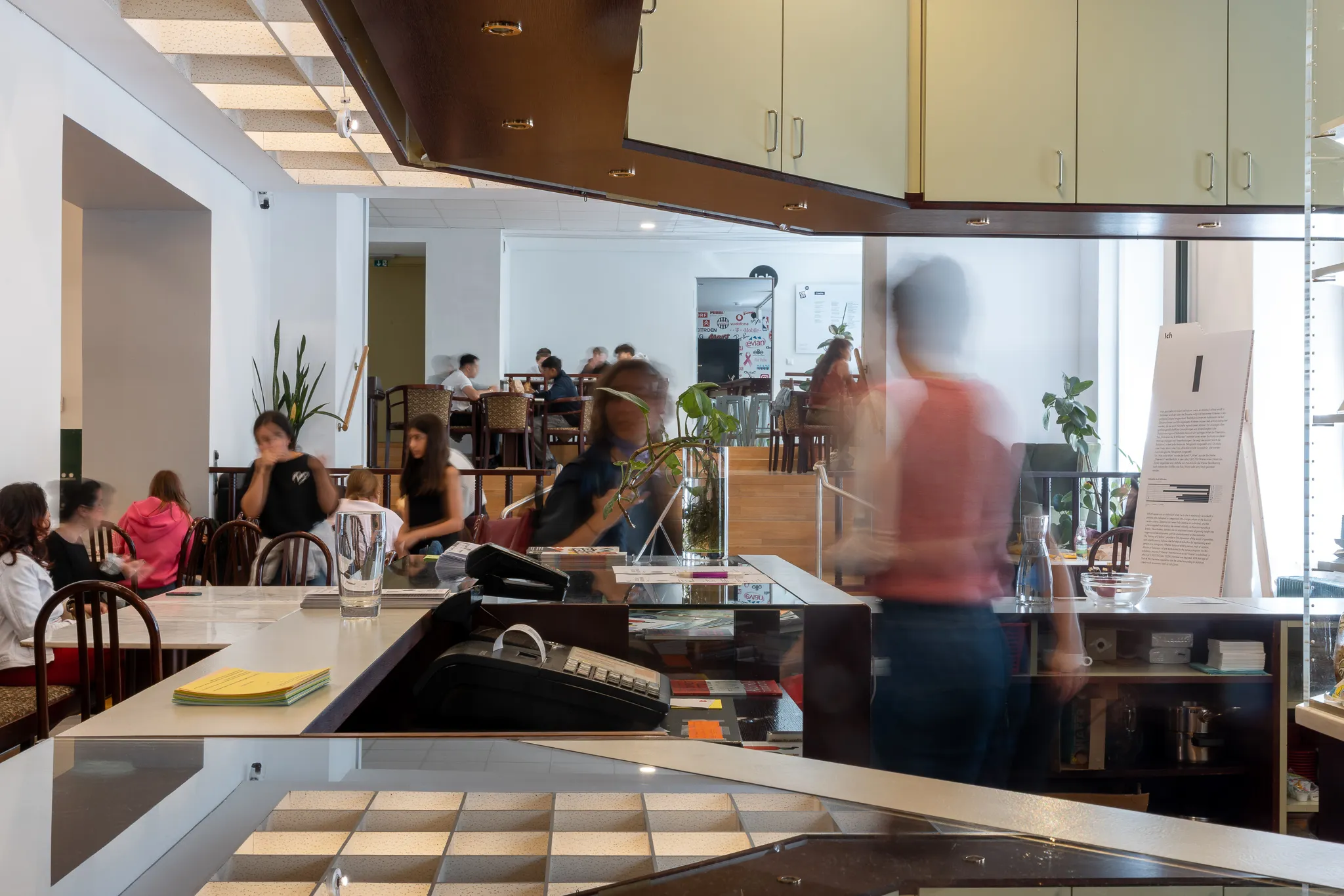 Interior of a museum with people seated at tables, glass partitions, and wooden cabinets
