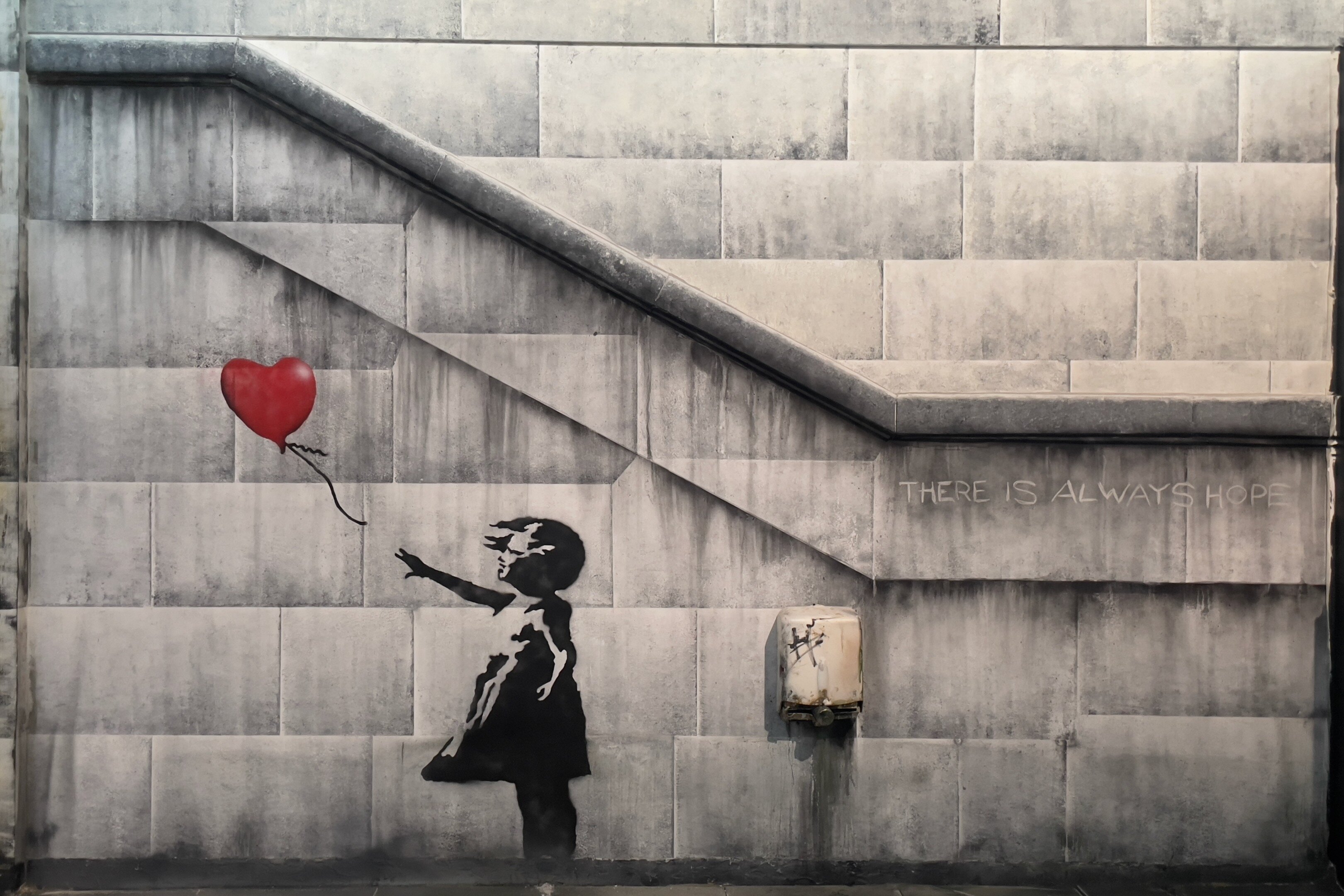 Silhouette of a girl reaching for a red heart balloon on a concrete wall with 'THERE IS ALWAYS HOPE' text
