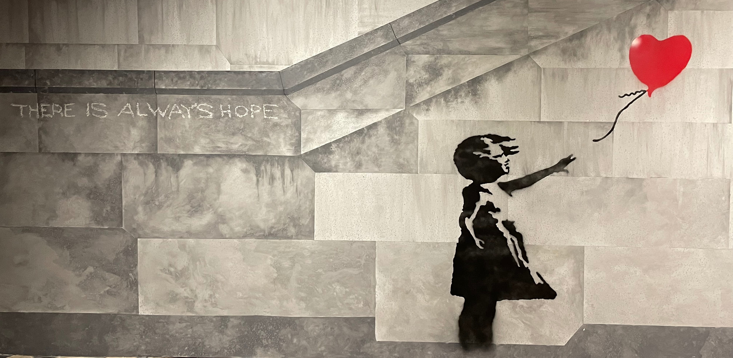 Silueta de una niña alcanzando un globo rojo en forma de corazón con el texto 'THERE IS ALWAYS HOPE' sobre escalones de piedra