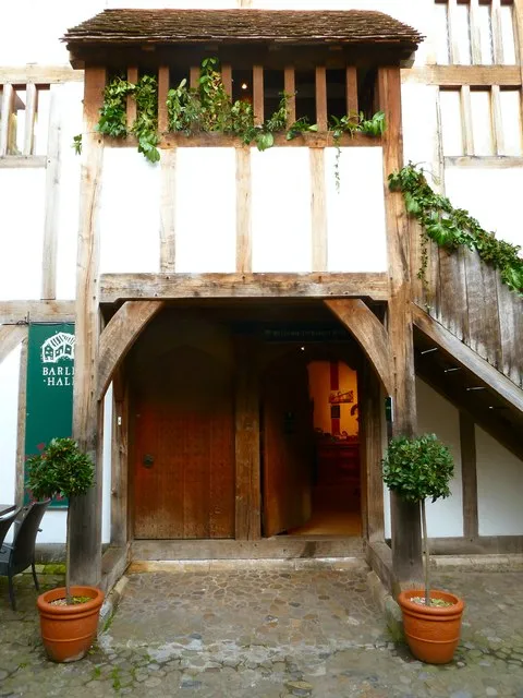 Middeleeuws vakwerkhuis met houten veranda, boogvormige ingang, klimop en twee potplanten in topvorm, met een Barley Hall-bord aan de linkerzijde